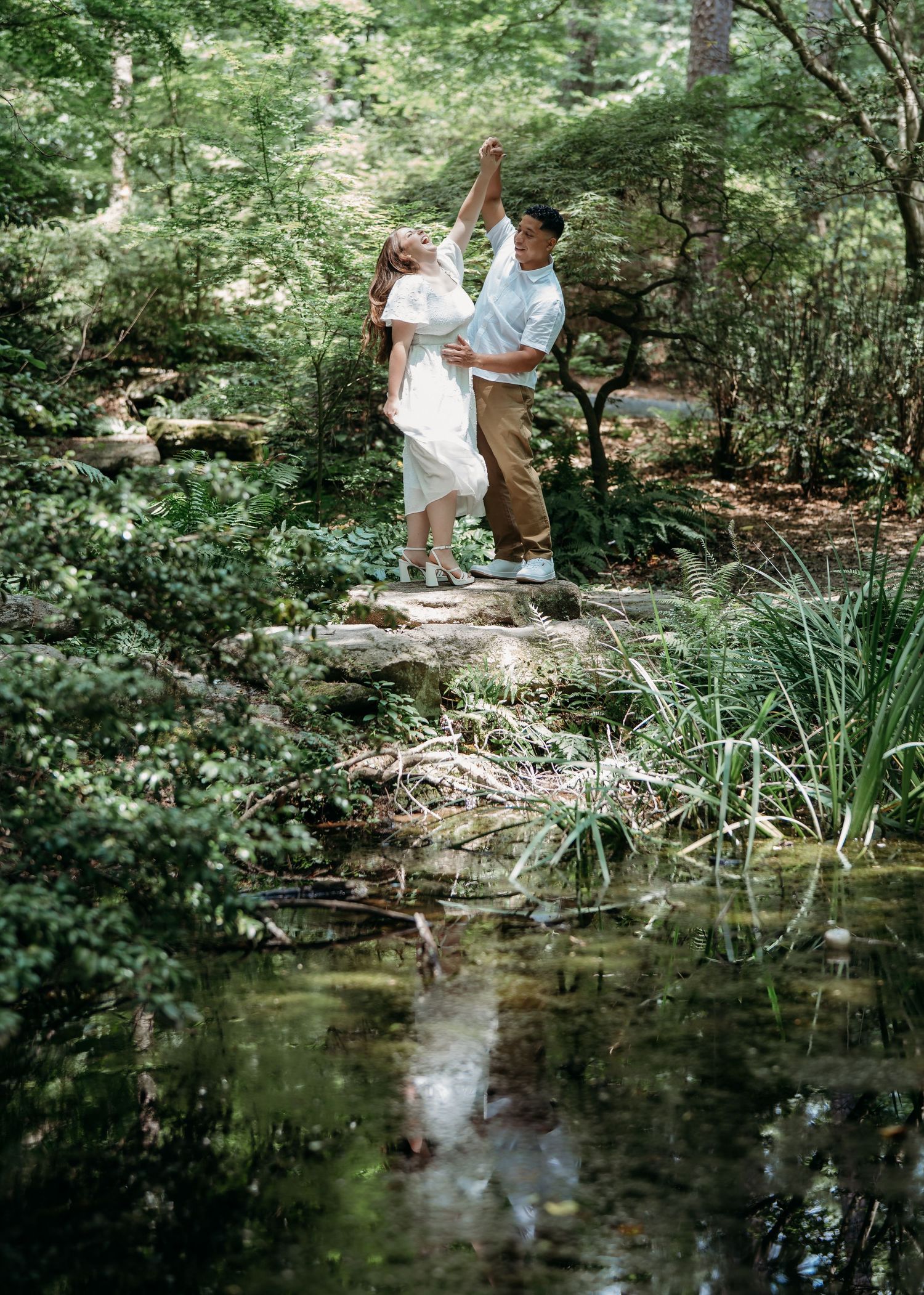 A peaceful woodland scene with a pond reflecting trees and foliage while people explore the natural setting.