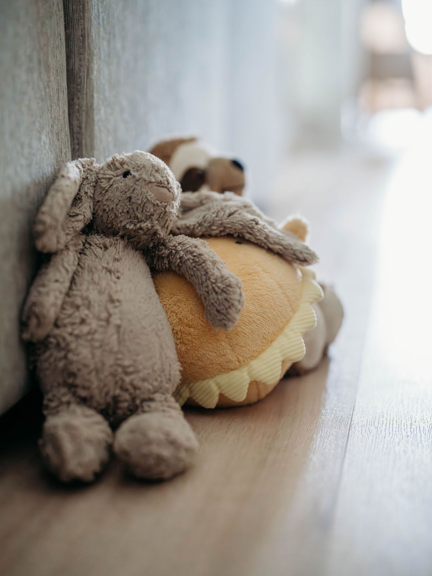A collection of soft plush teddy bears lying on a wooden floor in diminishing focus.