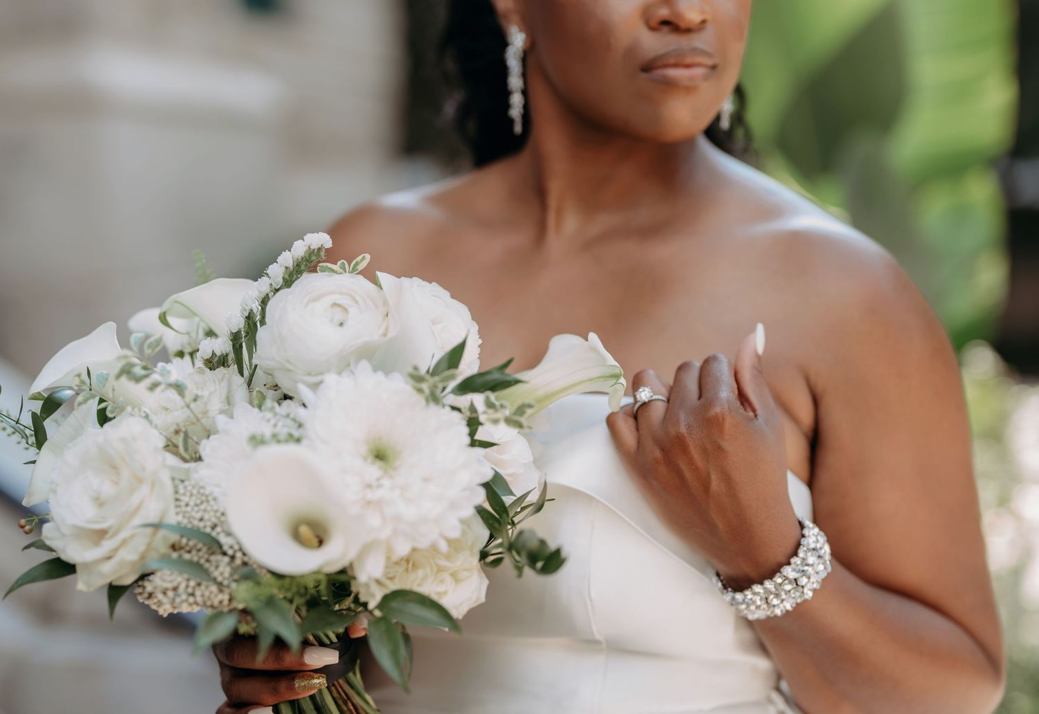 Elegant bridal bouquet of white peonies and roses paired with a delicate pearl bracelet and strapless wedding dress.