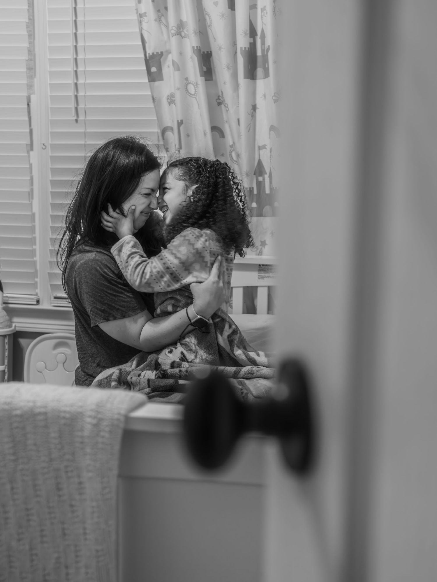 A black and white photo series showing a couple sharing intimate moments by a window.