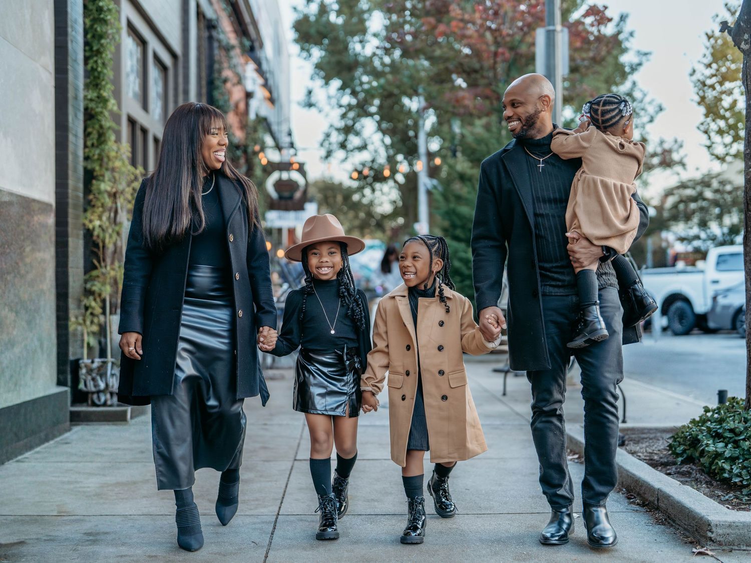 People walking together on a sidewalk wearing winter coats and boots on an urban street.