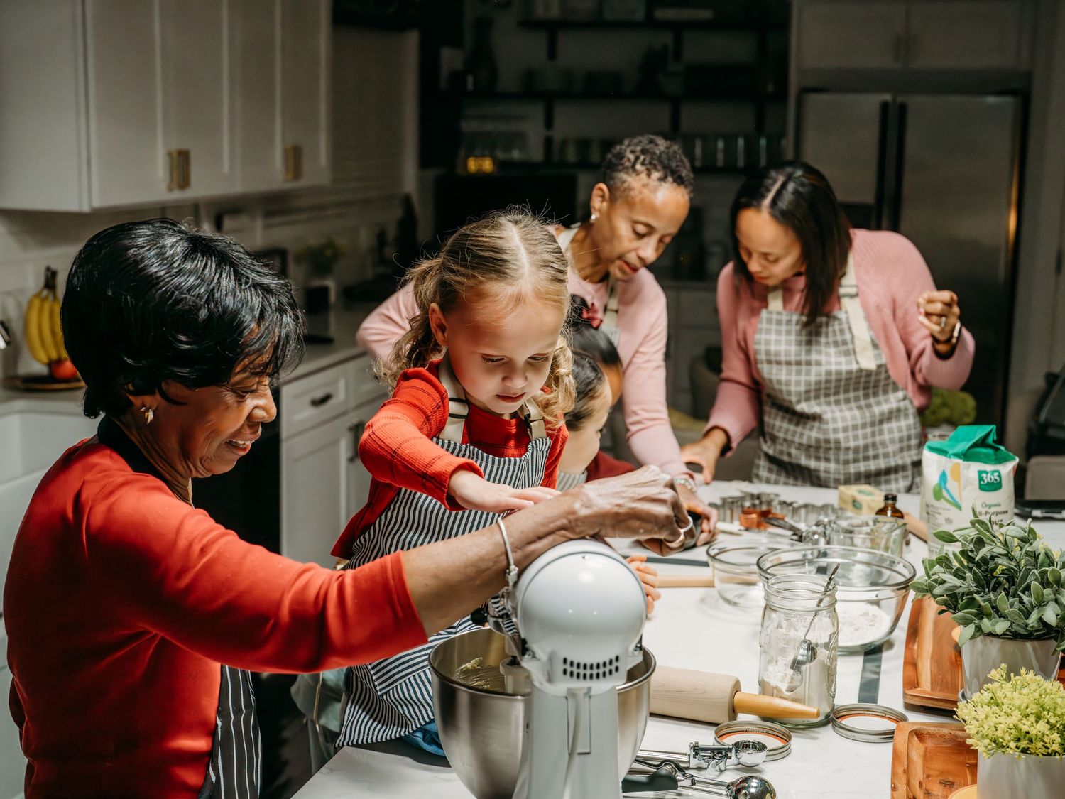 A family bakes together in their kitchen, working with flour and ingredients on a counter while sharing quality time.