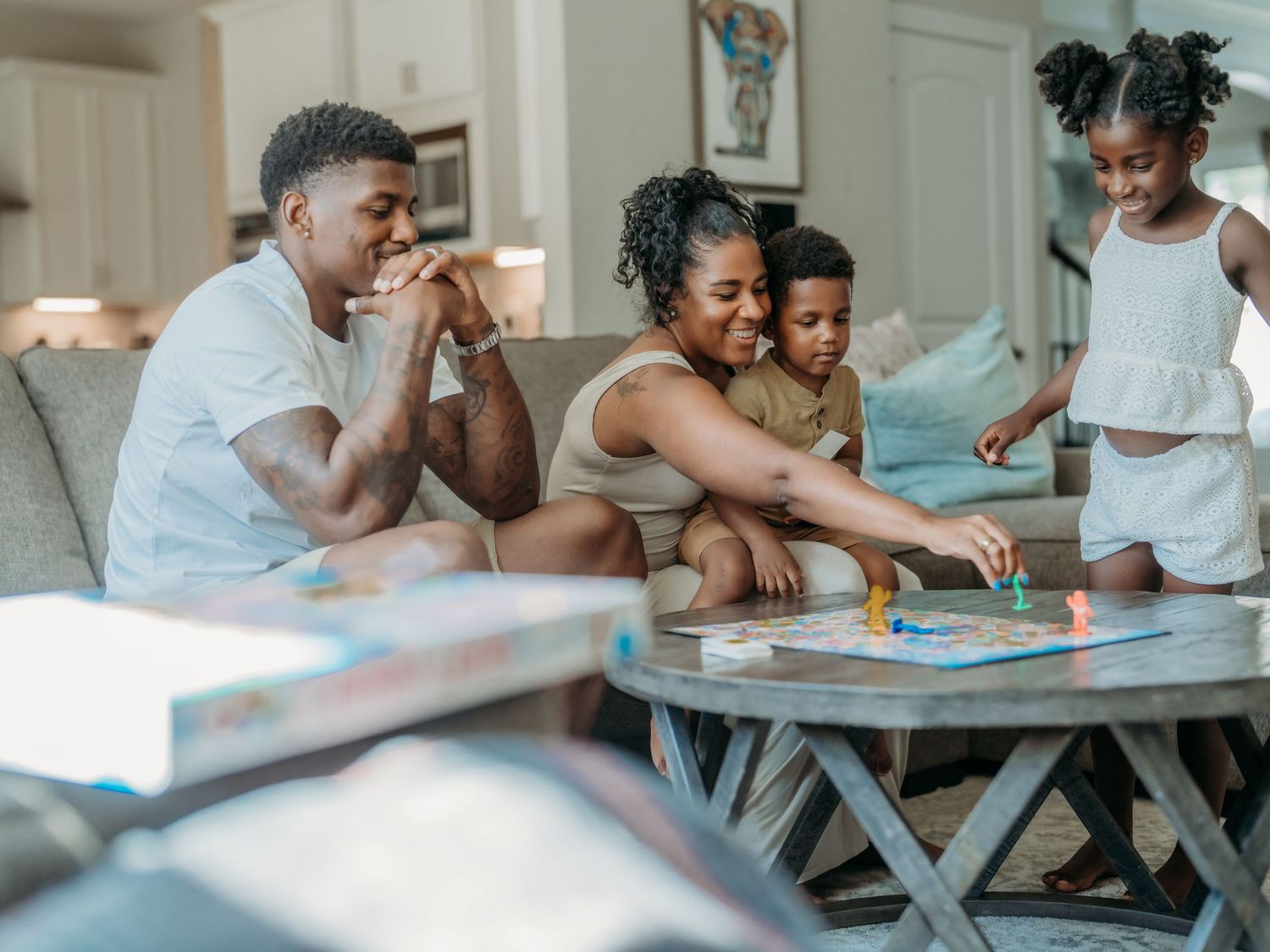 A family enjoys playing a board game together at their coffee table in their bright living room.