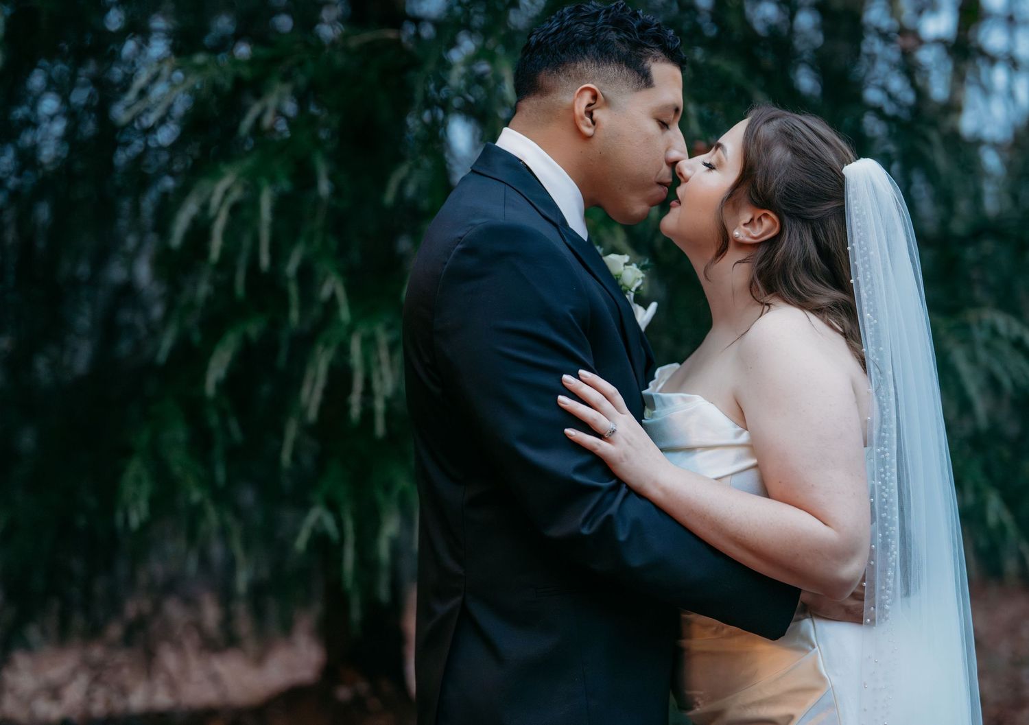 A romantic wedding couple shares tender kisses in a series of black and white outdoor portraits.