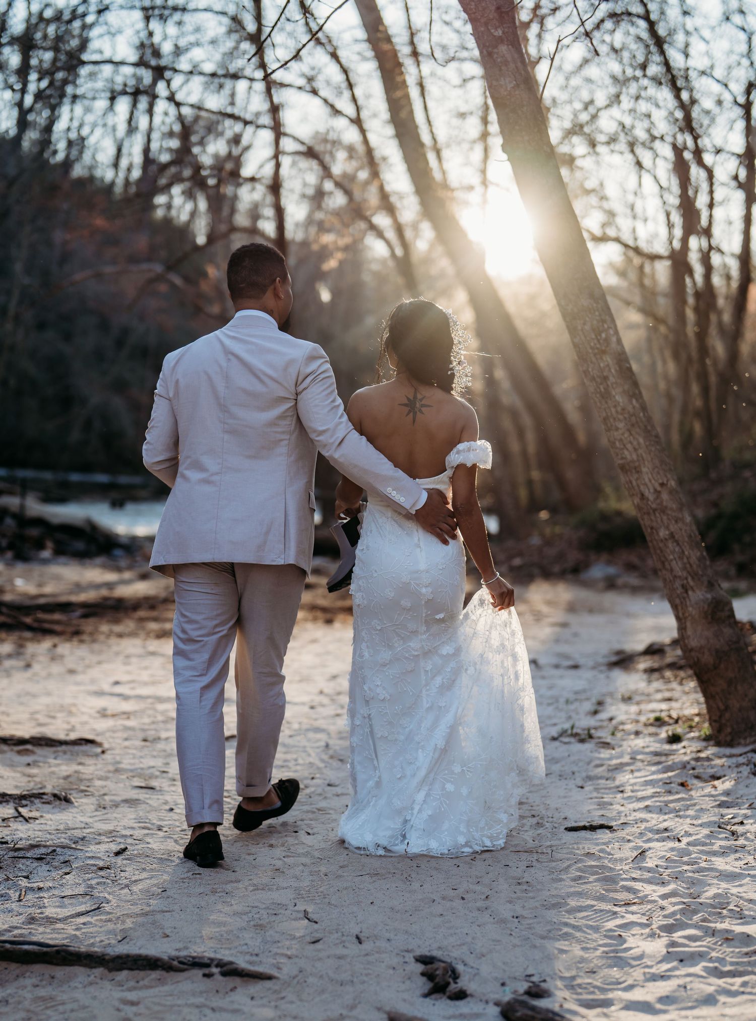 Silhouetted couple walking along sandy beach during golden hour sunset in romantic wedding photography sequence.