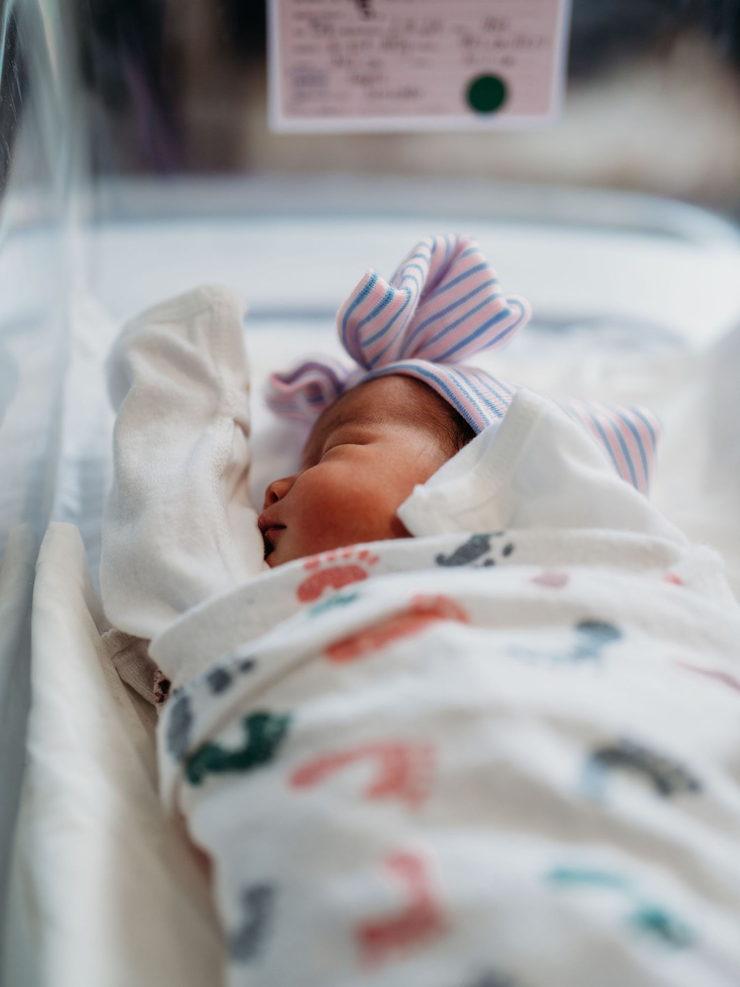 A series of connected photos showing a sleeping newborn baby swaddled in a striped hospital blanket.