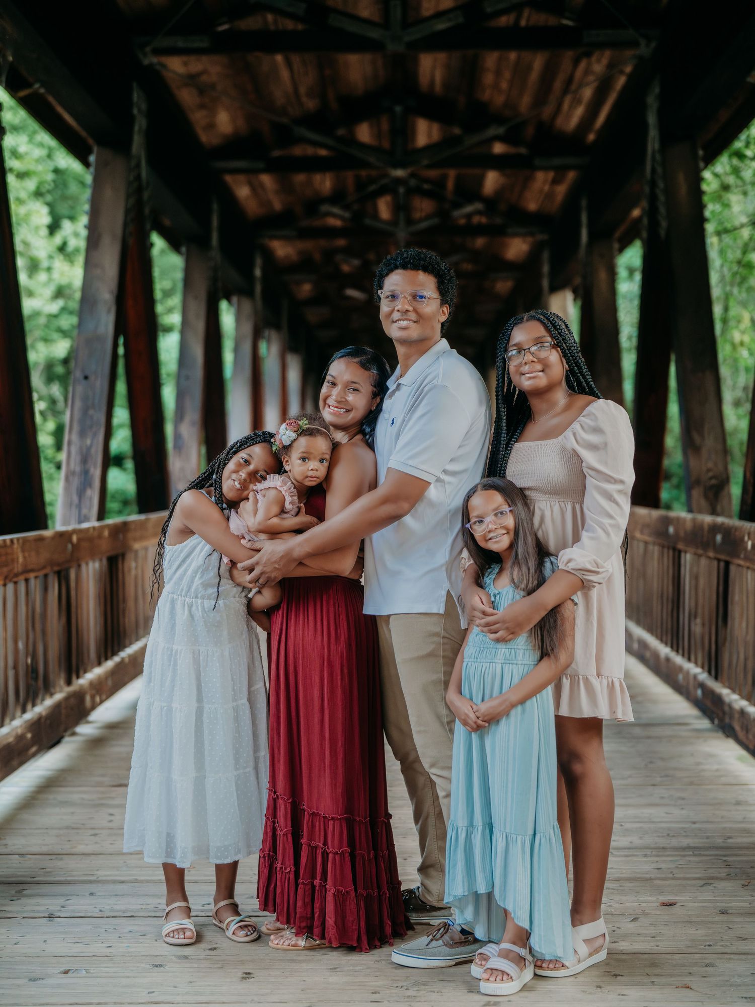 Family shares loving moments together in a series of candid photos on a rustic wooden covered bridge.