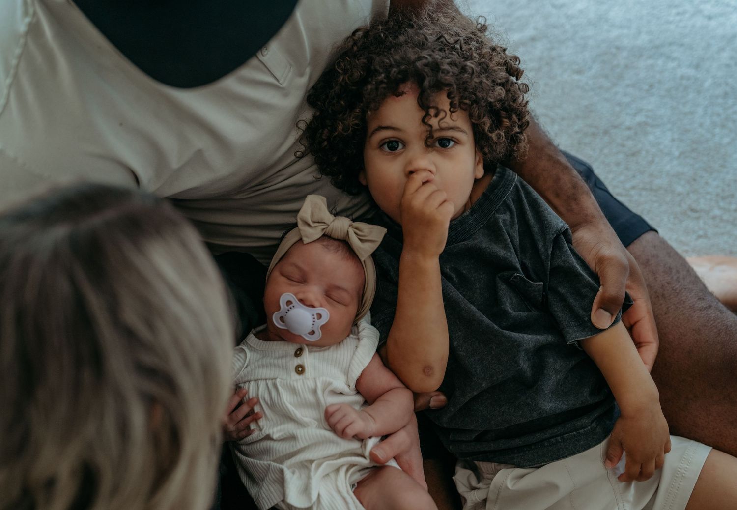 A series of candid moments show someone sitting and bonding with a curly-haired child on a couch.
