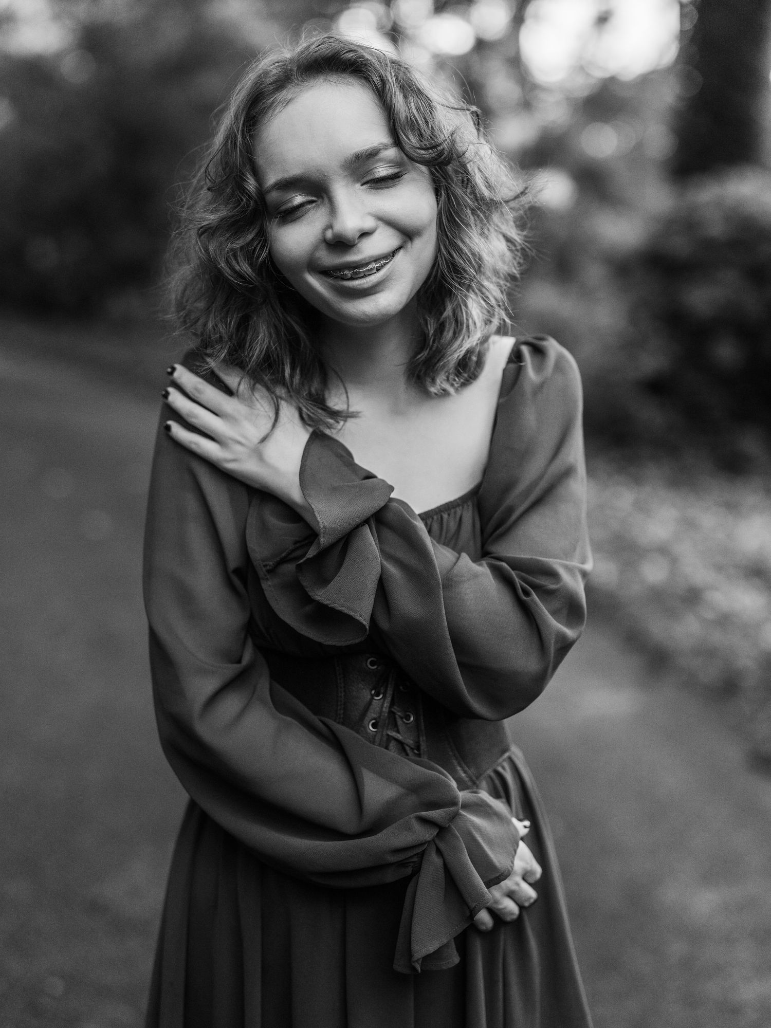 A split set of black and white artistic portrait photos showing someone in a dark dress with windblown hair.