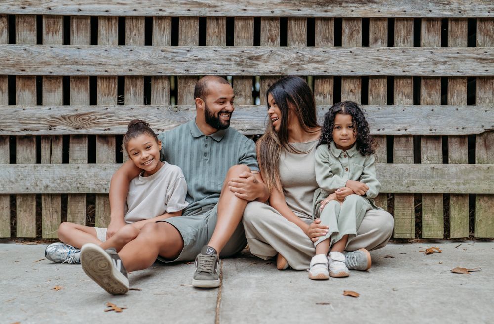 Two people sit together on wooden steps sharing an intimate moment in casual clothing.