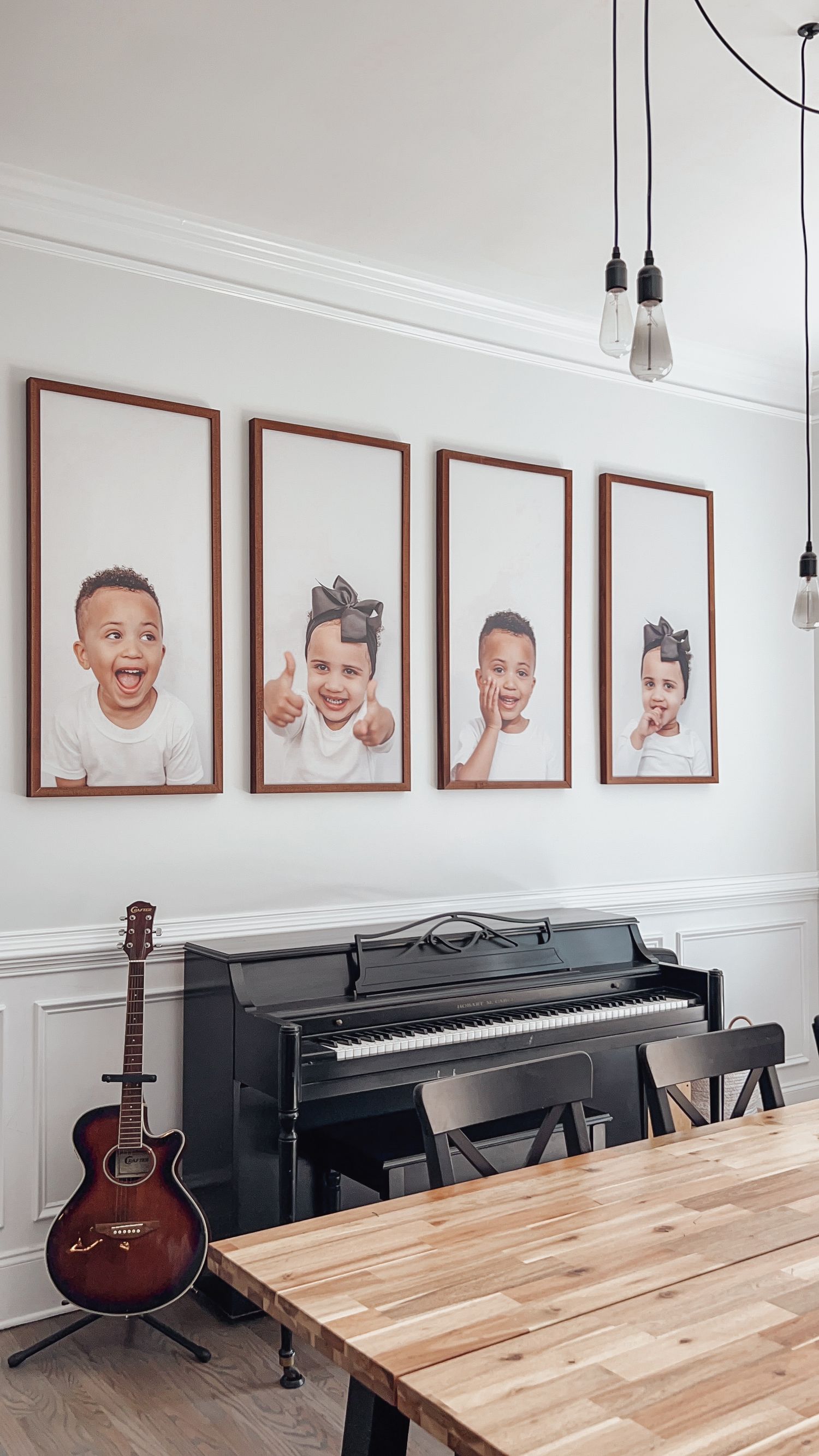 A modern music room with digital pianos, guitars, and framed portrait photographs hanging on a white wall.