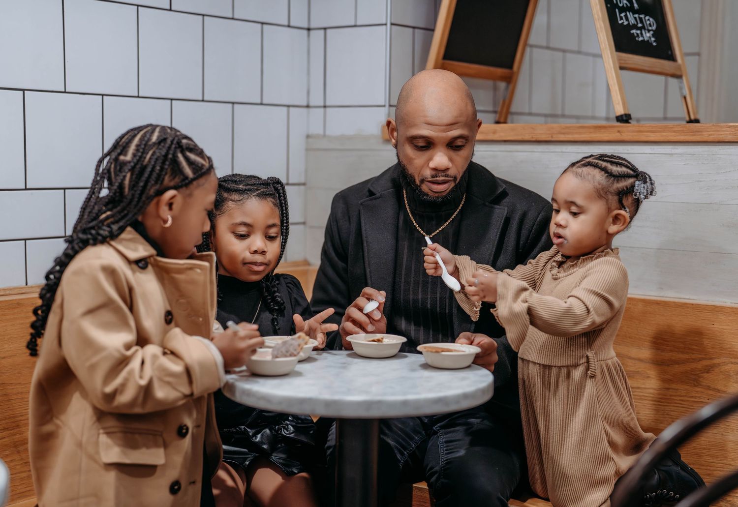 A family enjoys a meal together at a wooden dining table in a modern restaurant setting.