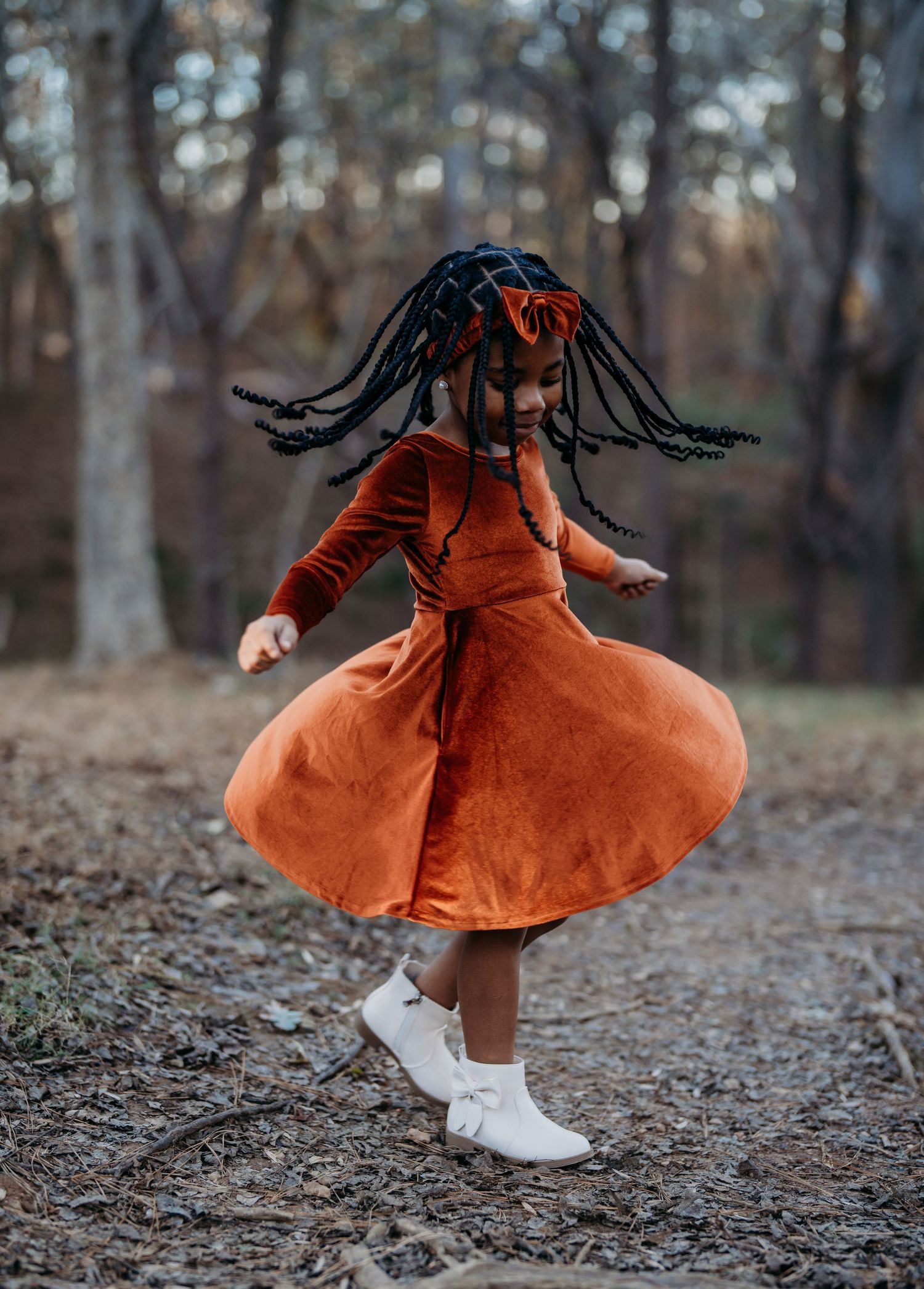 A sequence of twirling dance movements in a burnt orange dress amidst fallen leaves in a forest setting.