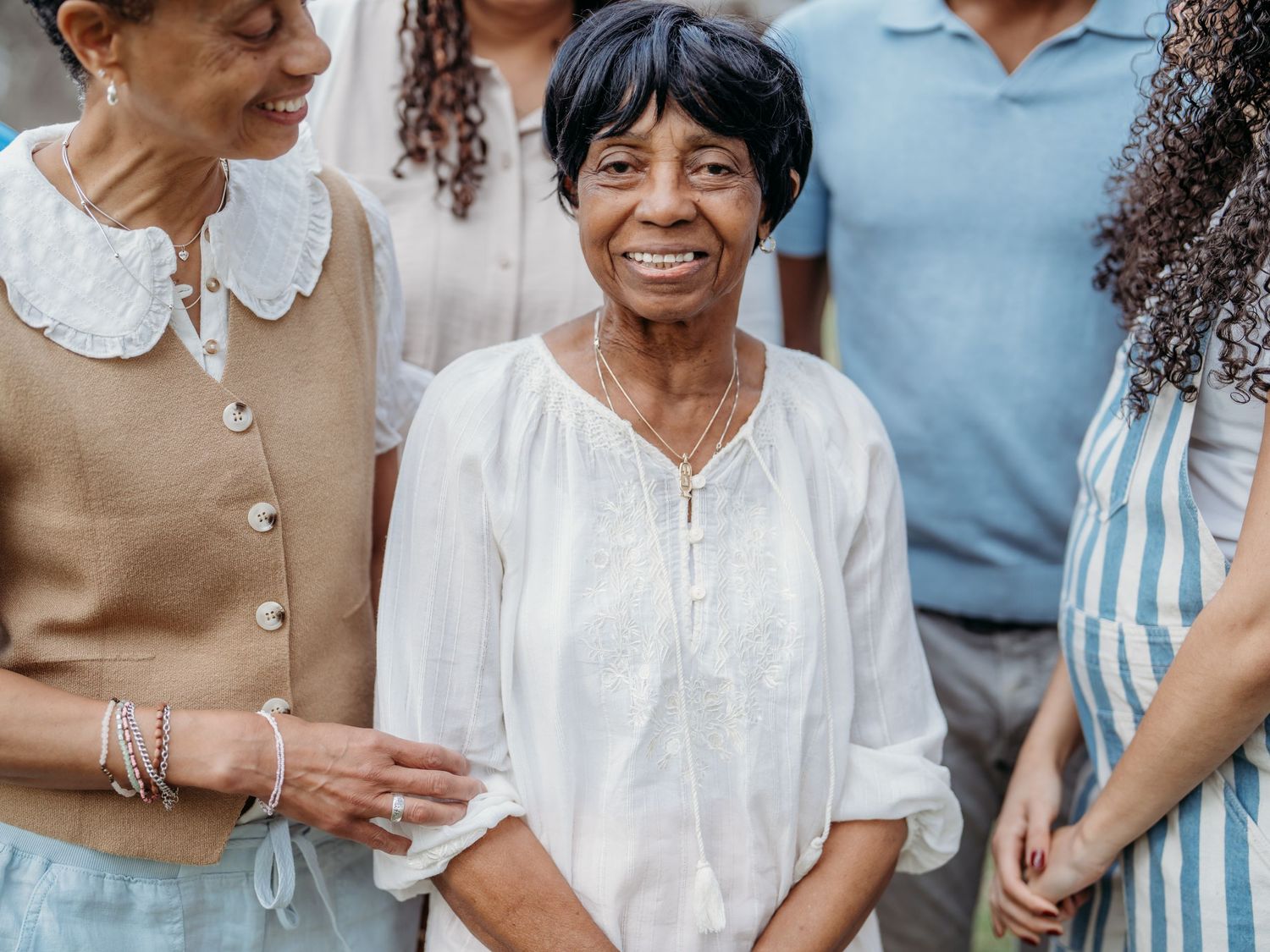 Diverse group of people standing together smiling and enjoying each others company in casual attire.