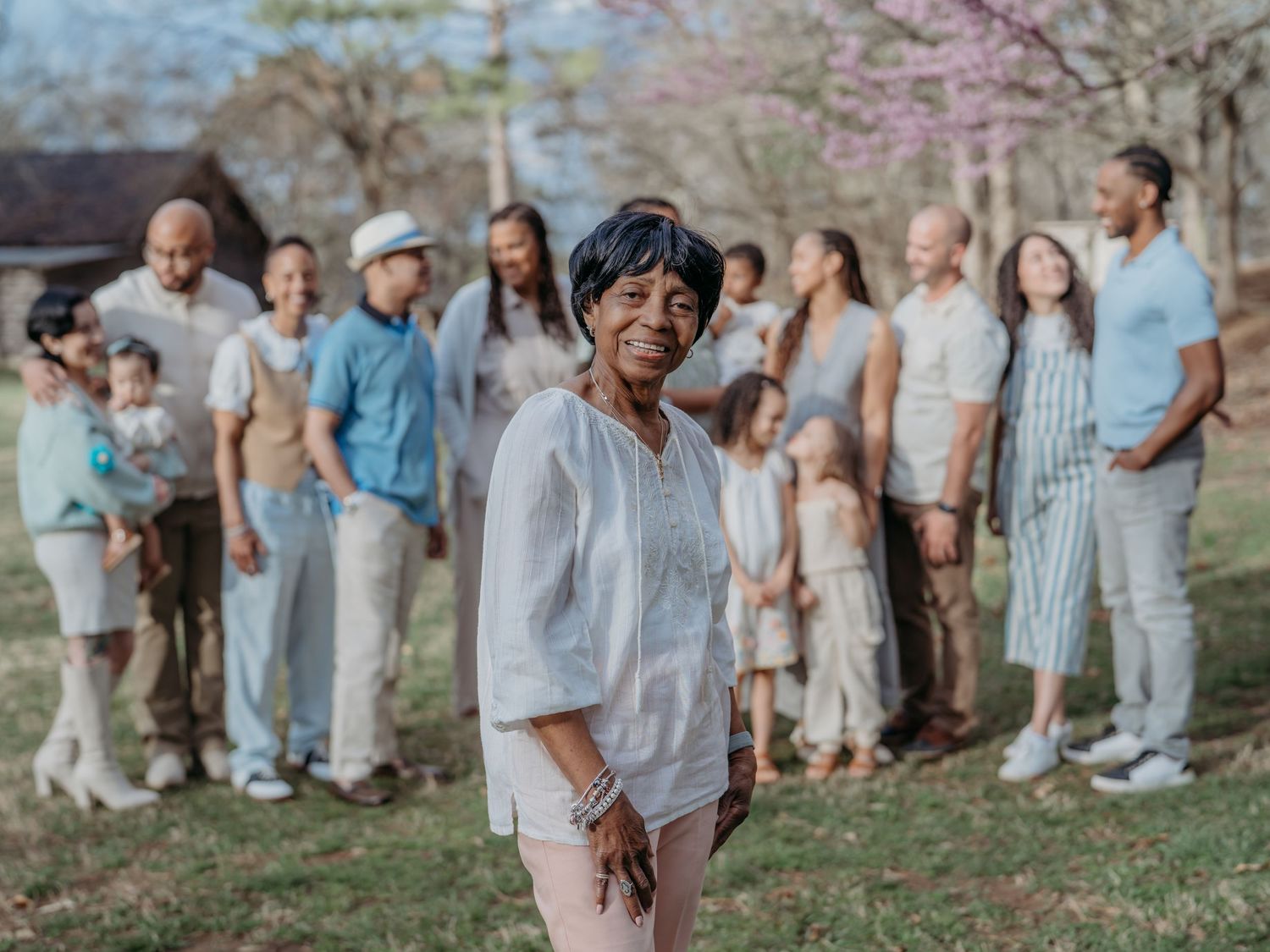 Extended family poses together outdoors during spring with blooming cherry blossoms in the background.