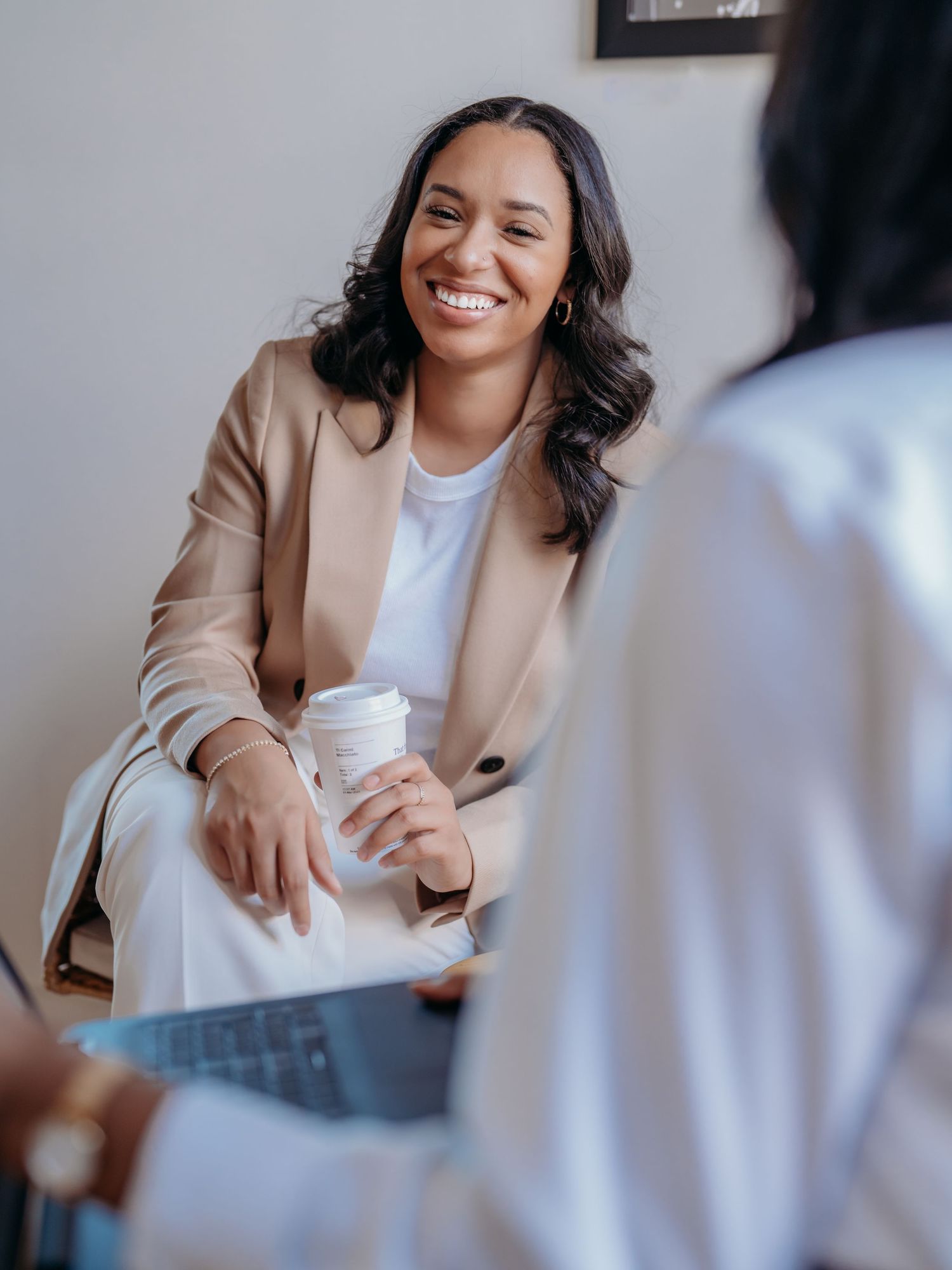Professional in a beige blazer and white shirt having an engaging business discussion at an office meeting.
