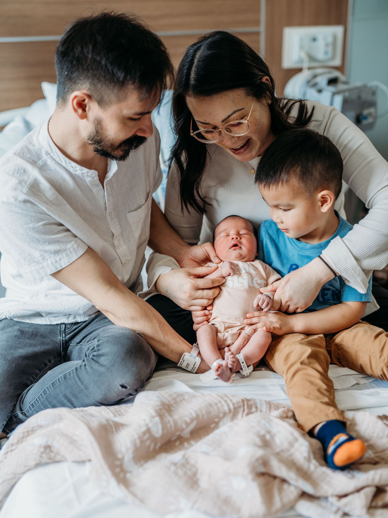 A series of candid family moments shown in connected photos of parents and children lying together on a bed.