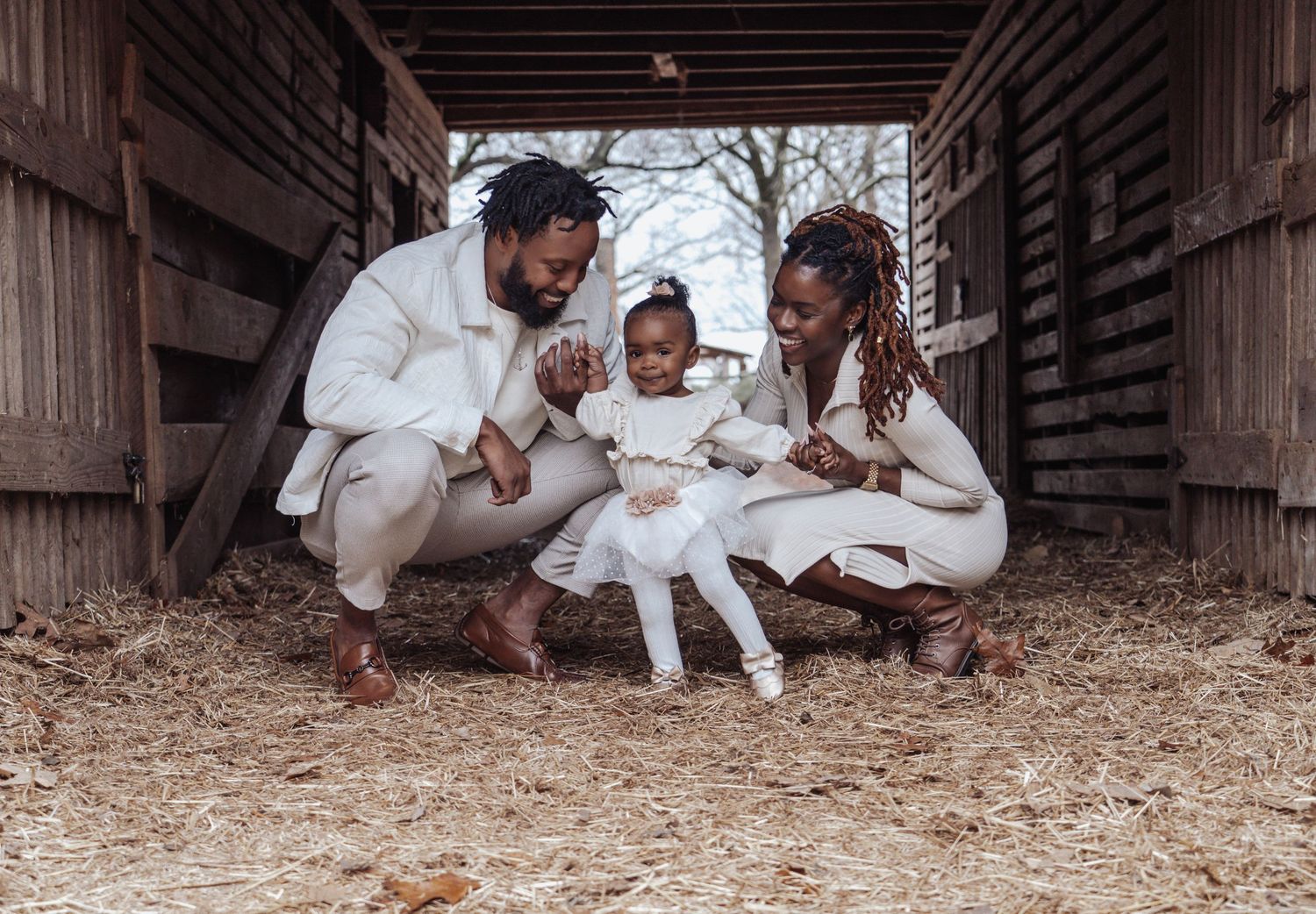 A family sits together in matching white outfits for a casual outdoor photo session.