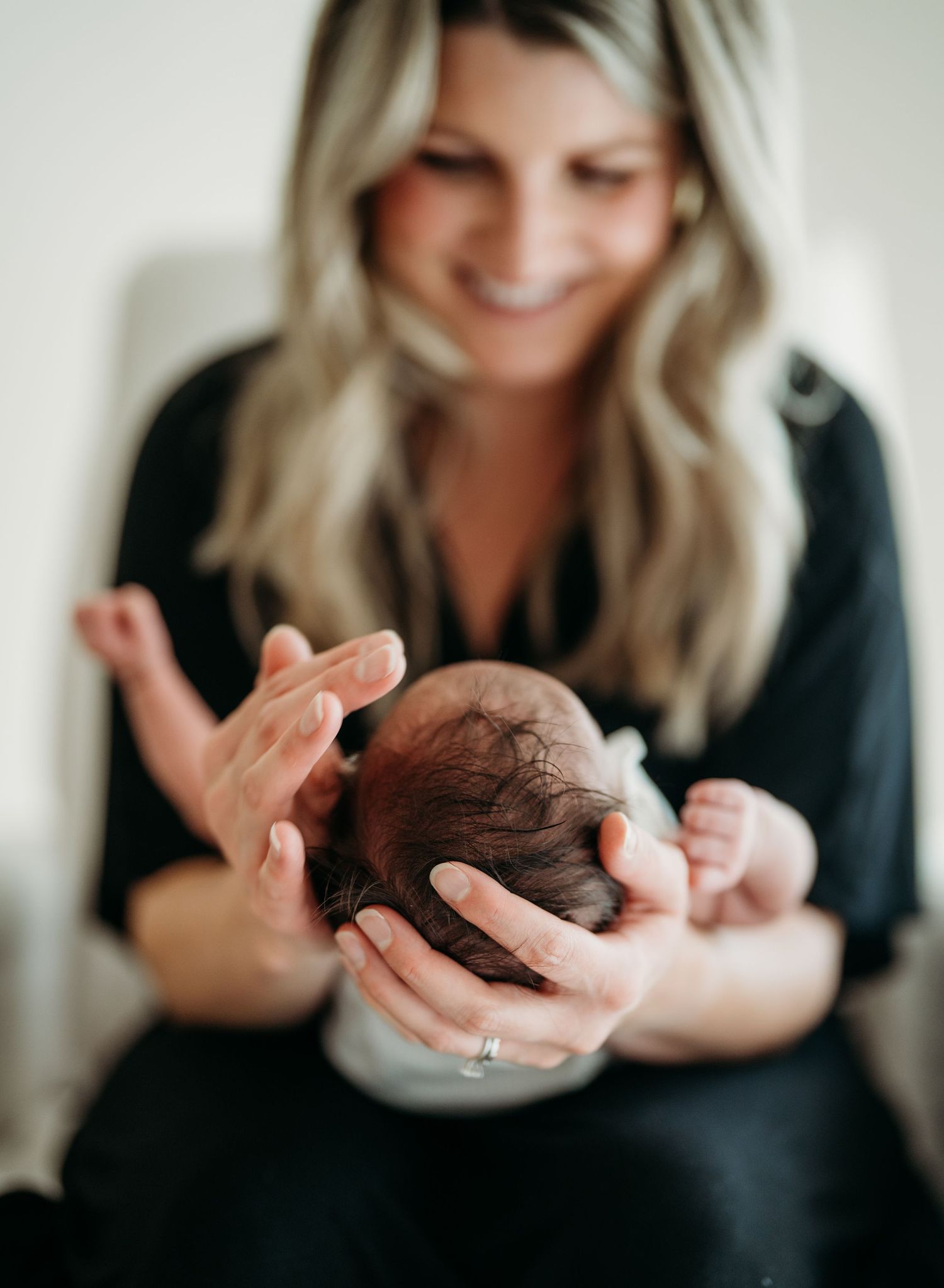 A series of photos showing a newborn baby being gently cradled and held in someone's hands against a light background.