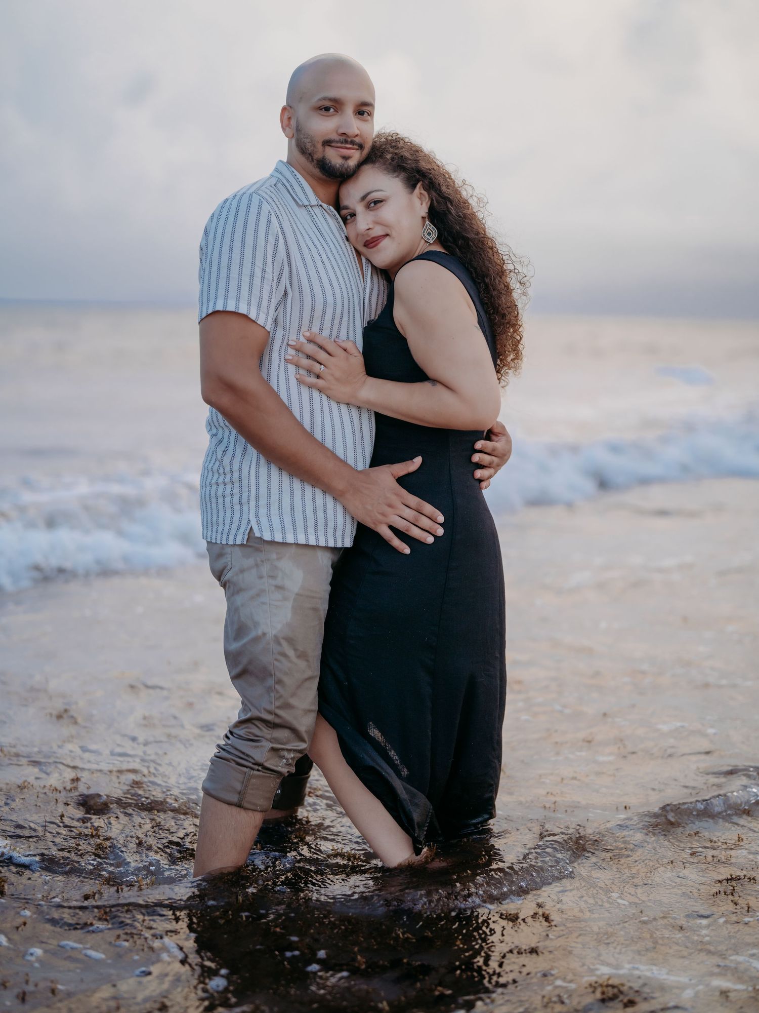 A couple shares an intimate moment sitting together on a sandy beach at sunset.