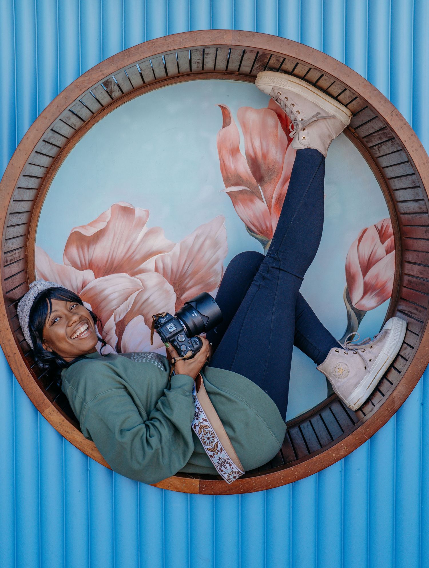 Three circular mirrors on a blue striped wall show someone playfully posing in different positions.