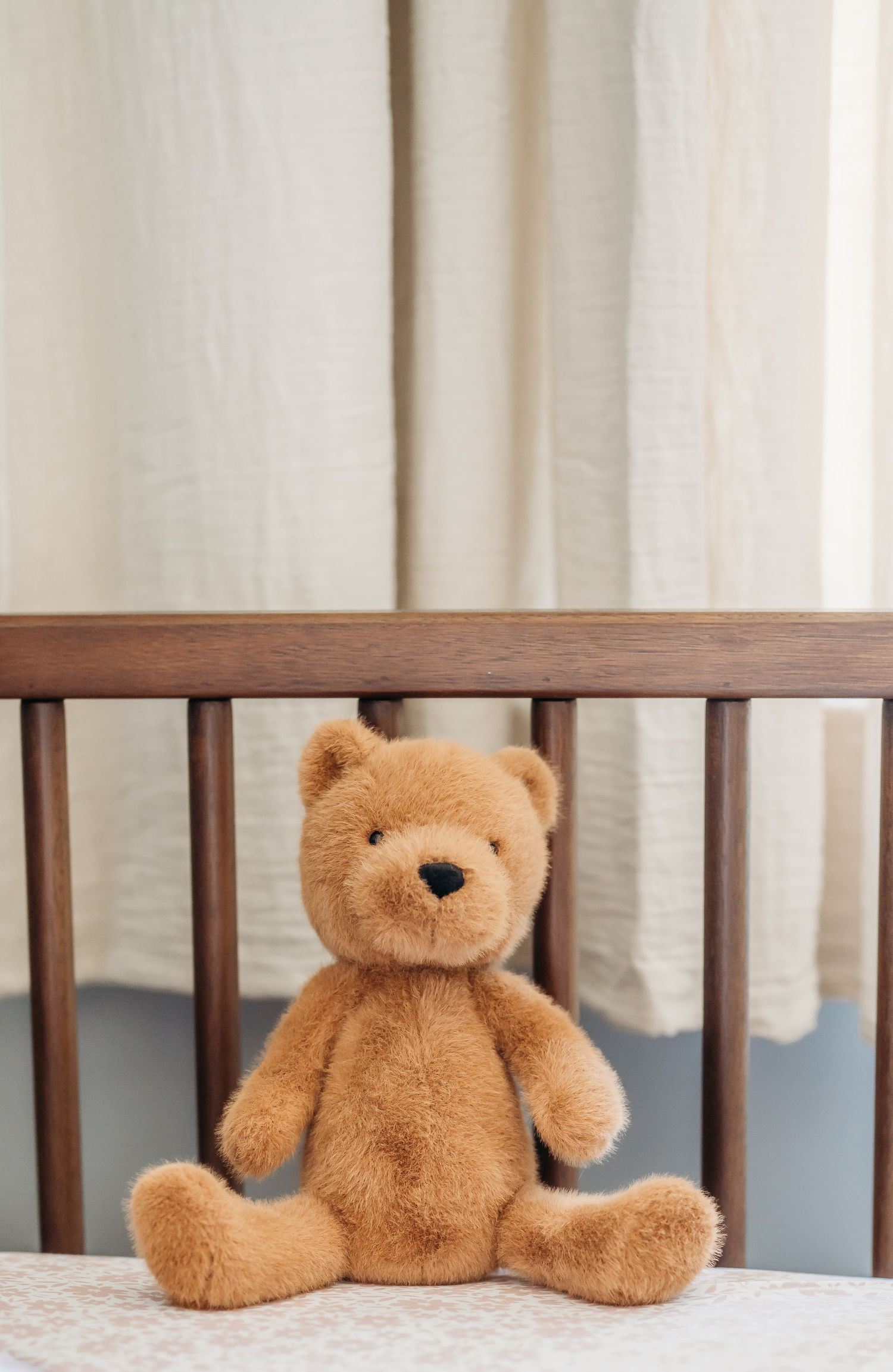 Three plush teddy bears sitting on a white surface against a light beige curtain background.