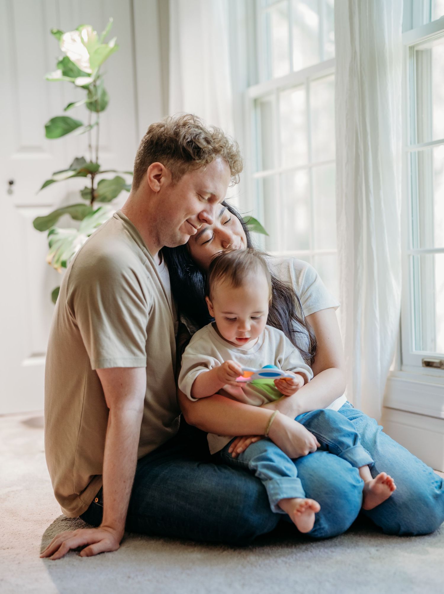 An intimate family moment by a bright window with natural light streaming in.