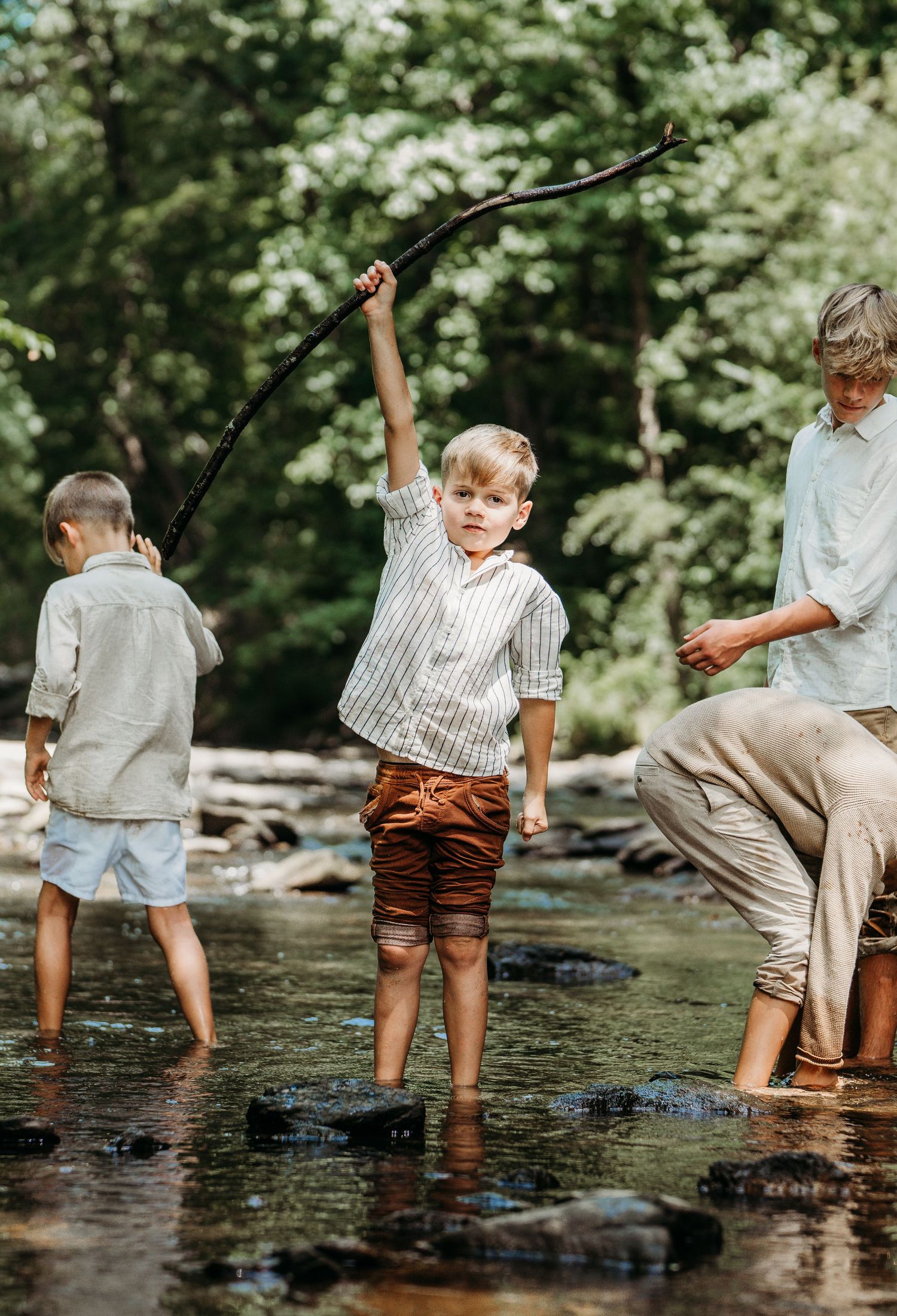 Three people standing in shallow stream water while fishing together on a summer day in nature.