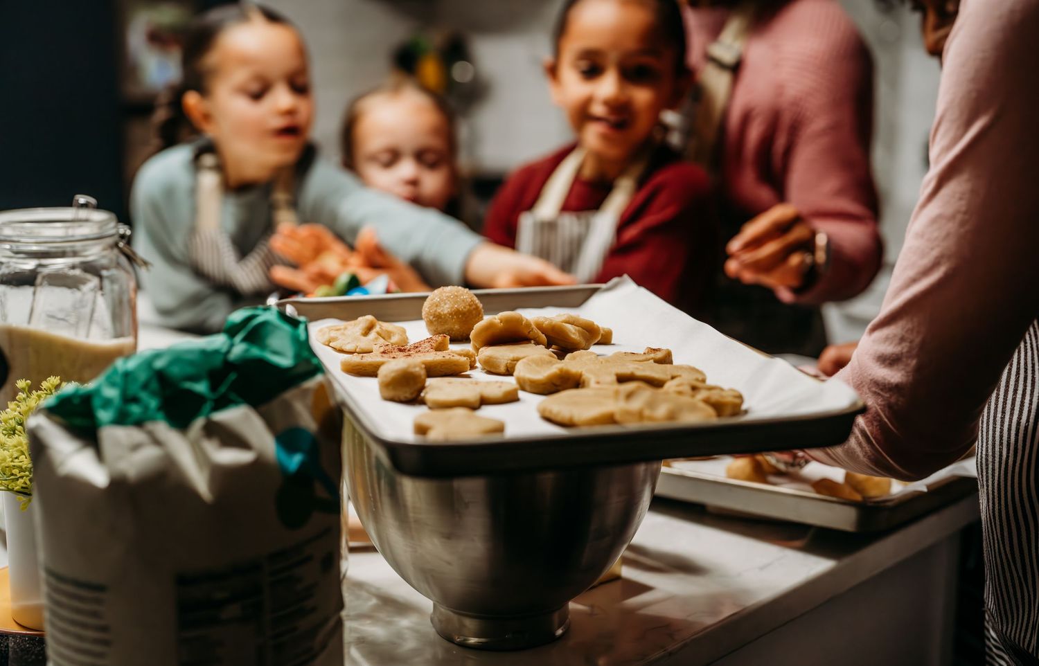 A plate of freshly baked cookies on a kitchen counter as people gather around to enjoy them together.
