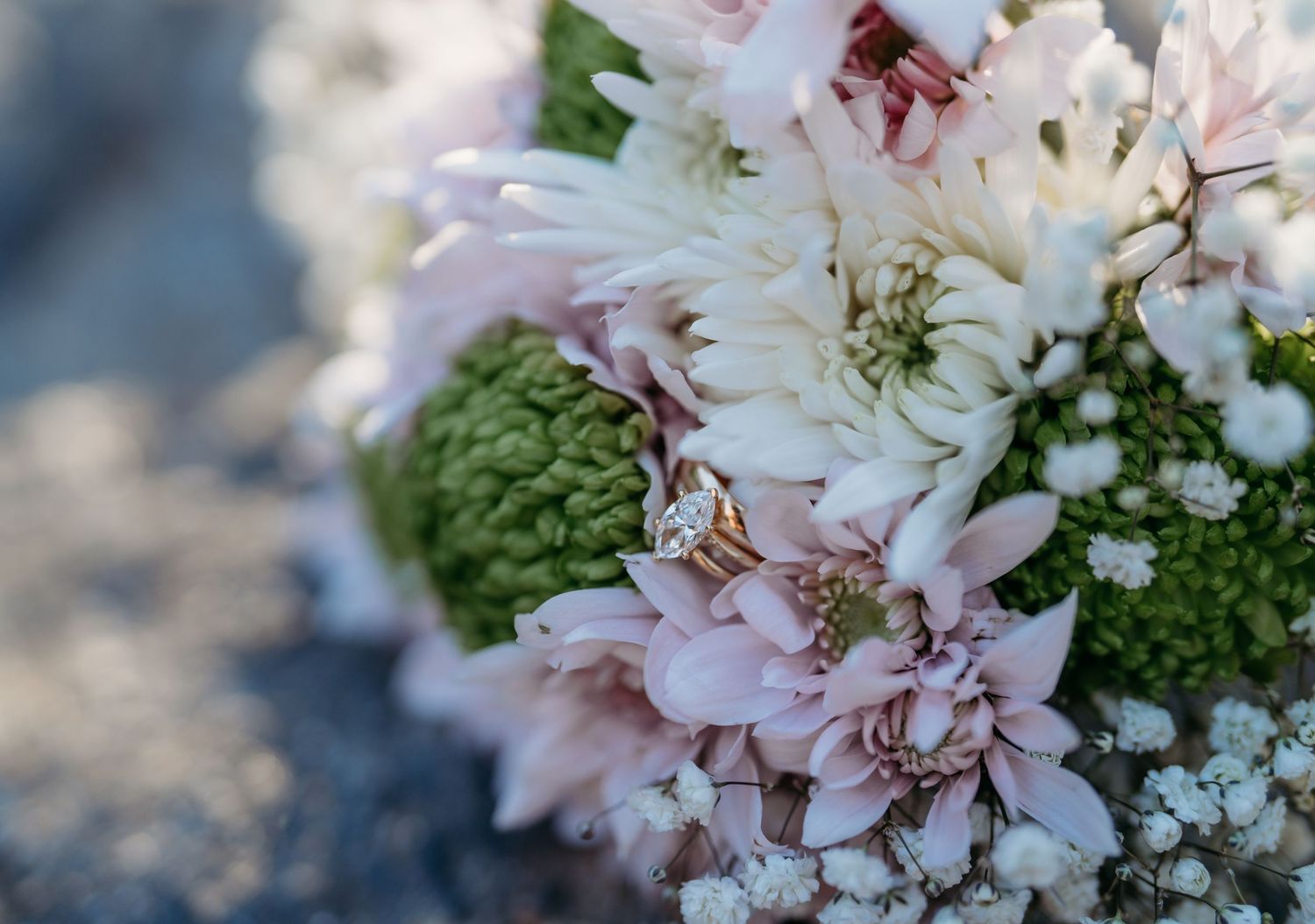 Delicate arrangement of white and pink flowers with green accents in soft focus against a blurred background.