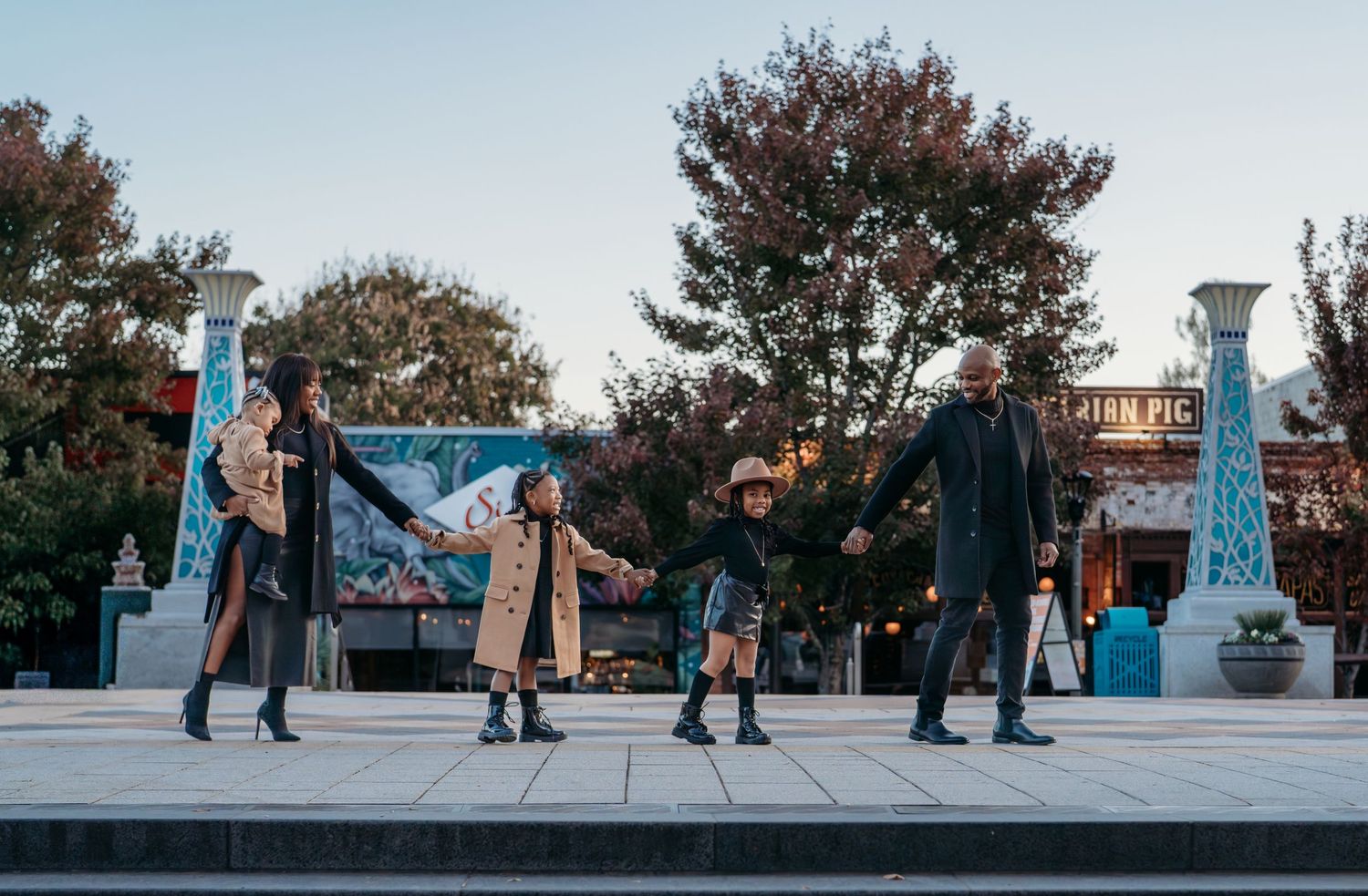 A family holding hands as they walk on the backdrop of a cool downtown scene.