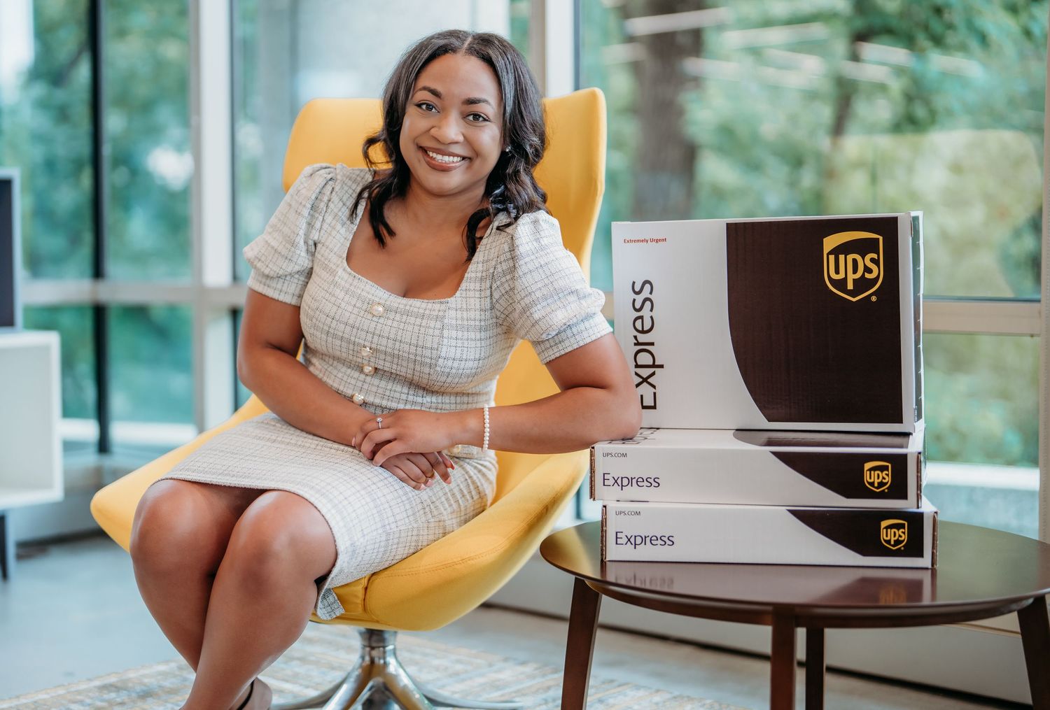 Person in casual attire sits at desk with UPS shipping boxes while working on laptop computer.