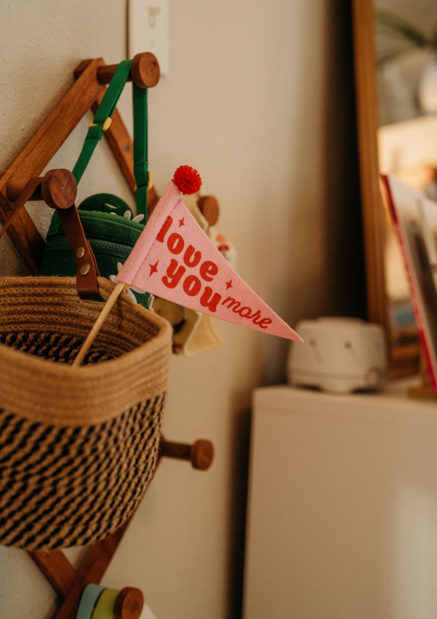 A small red and white 'I love you' pennant flag sits in a woven basket with green and wooden accents.