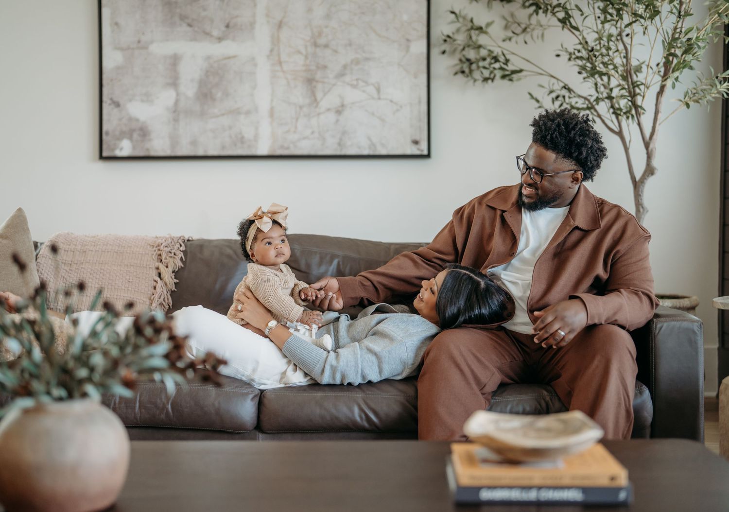 A tender moment shared between parent and child relaxing together on a gray couch in a modern living room.