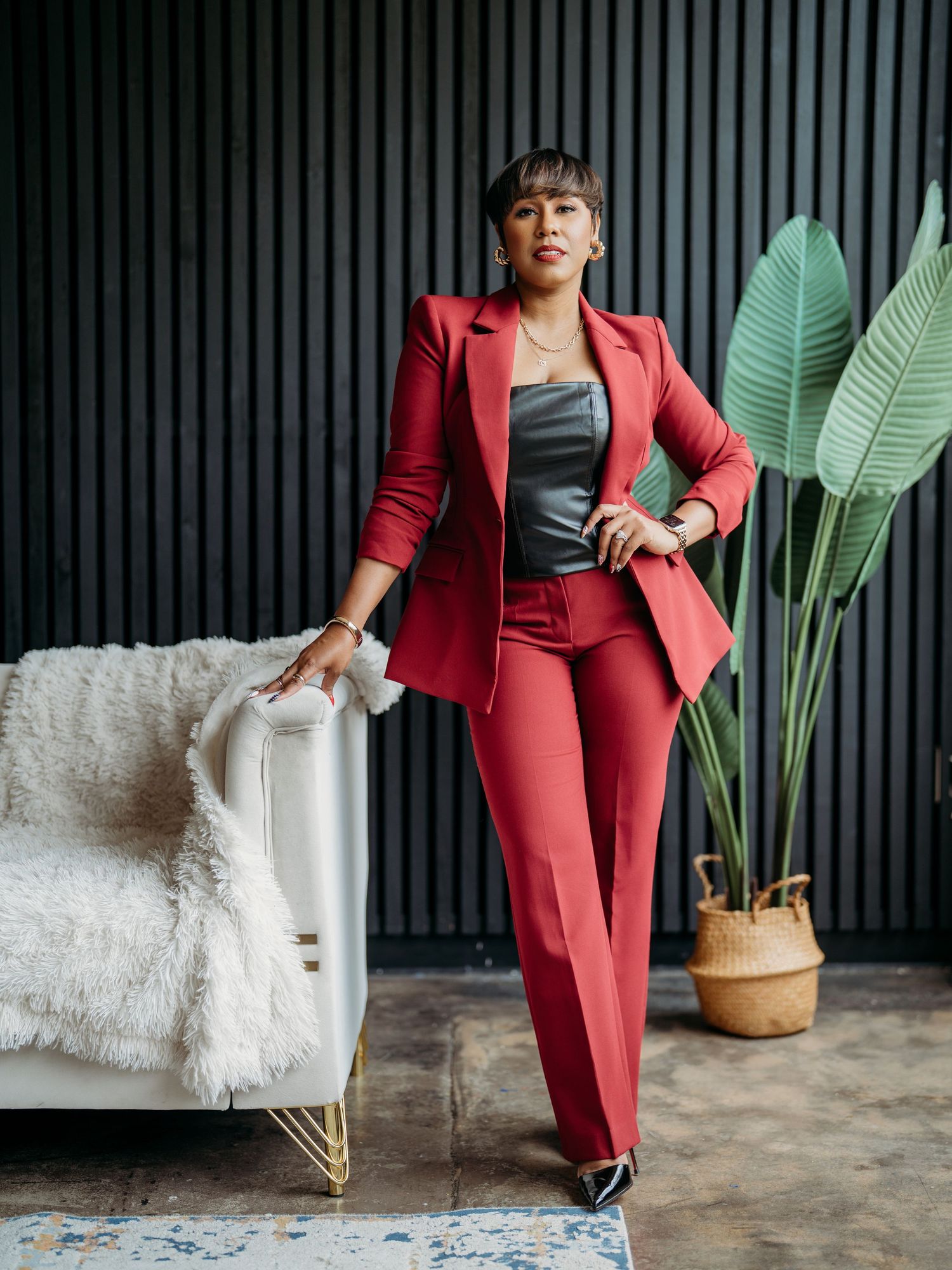 Professional fashion photo series showing a red business suit styled with white sneakers against a dark striped backdrop.