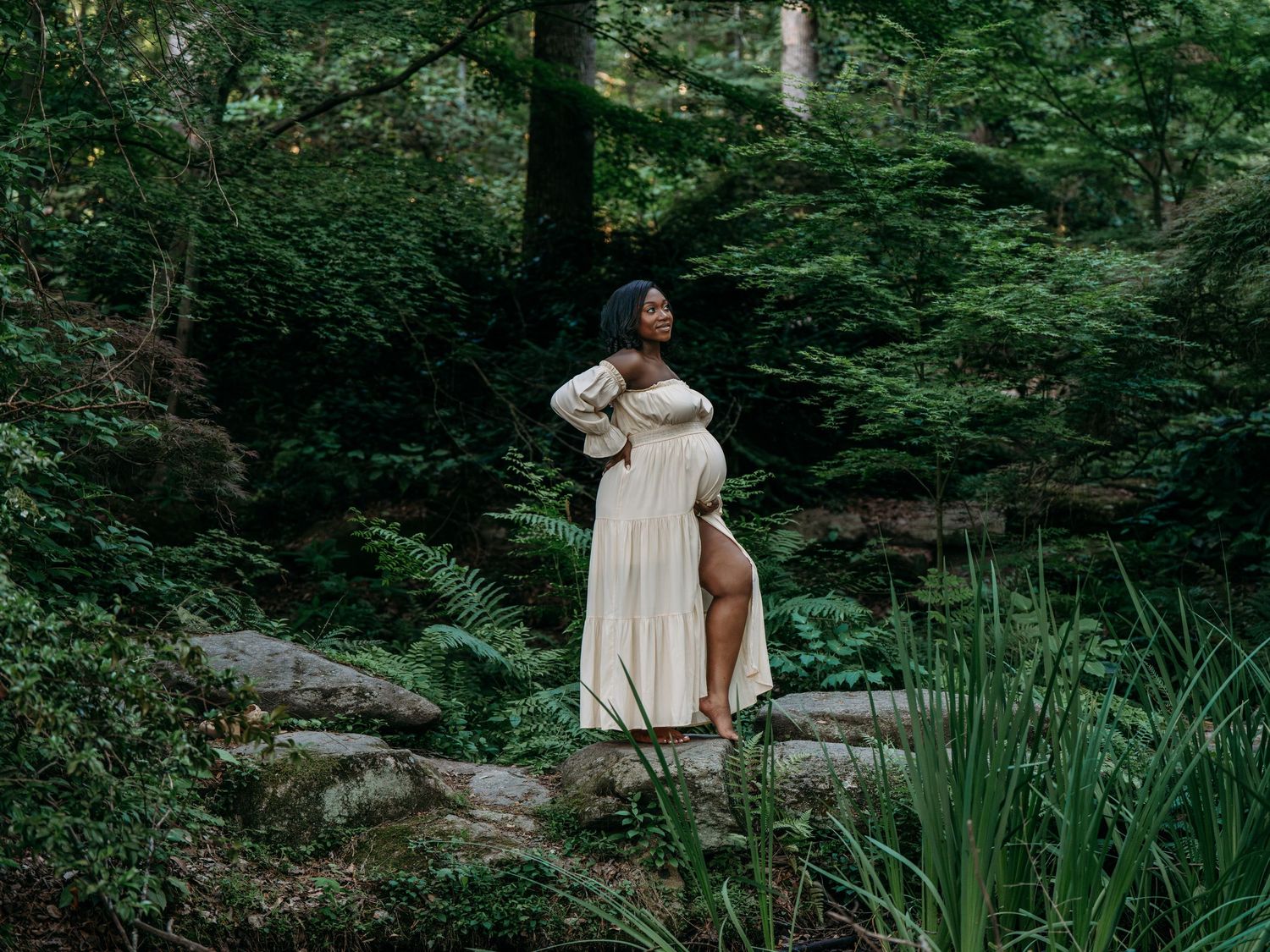 A dreamy maternity photo in a forest setting with flowing cream dress.