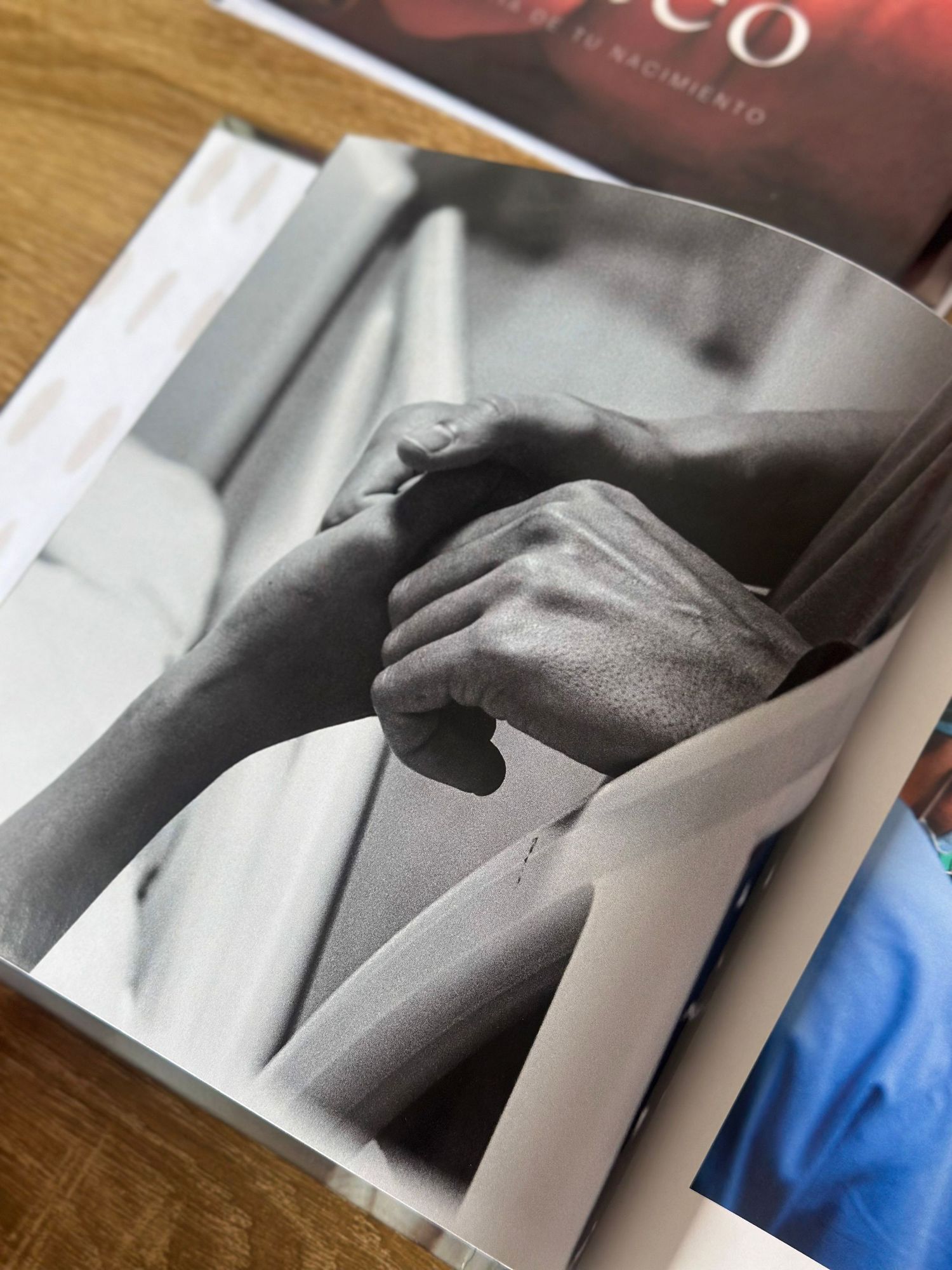 Black and white photo in a book showing two hands gently clasped together, symbolizing connection and birth.