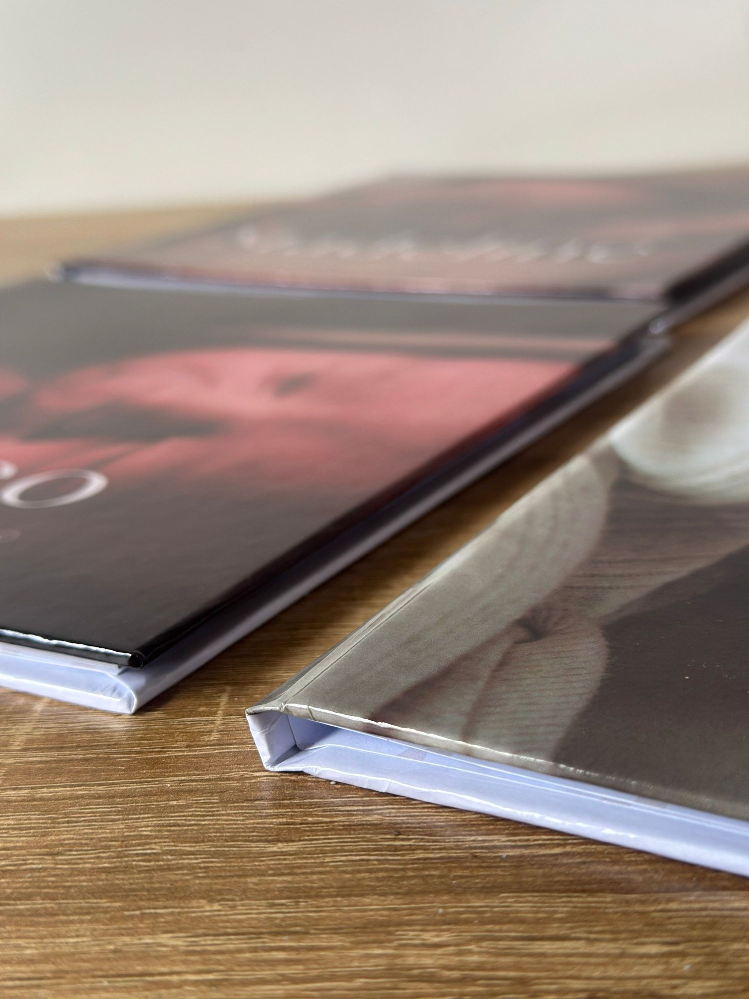 Close-up of stacked photo books with glossy covers on a wooden surface, showcasing professional print quality.