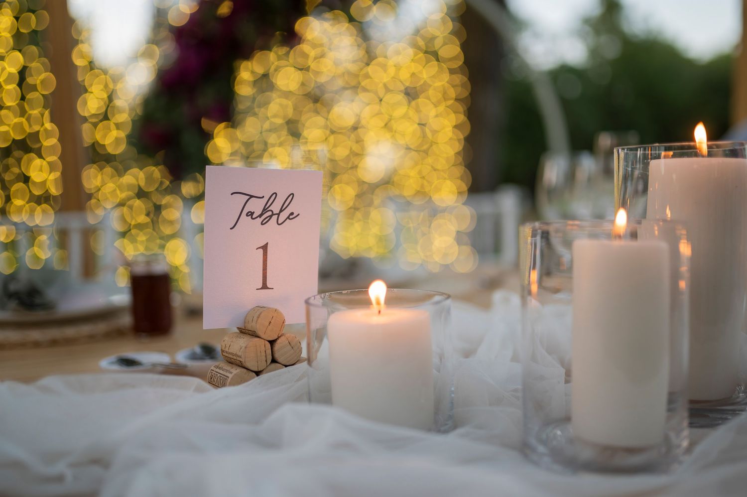 White votive candles and delicate name cards create an elegant table setting with golden autumn trees in the background.