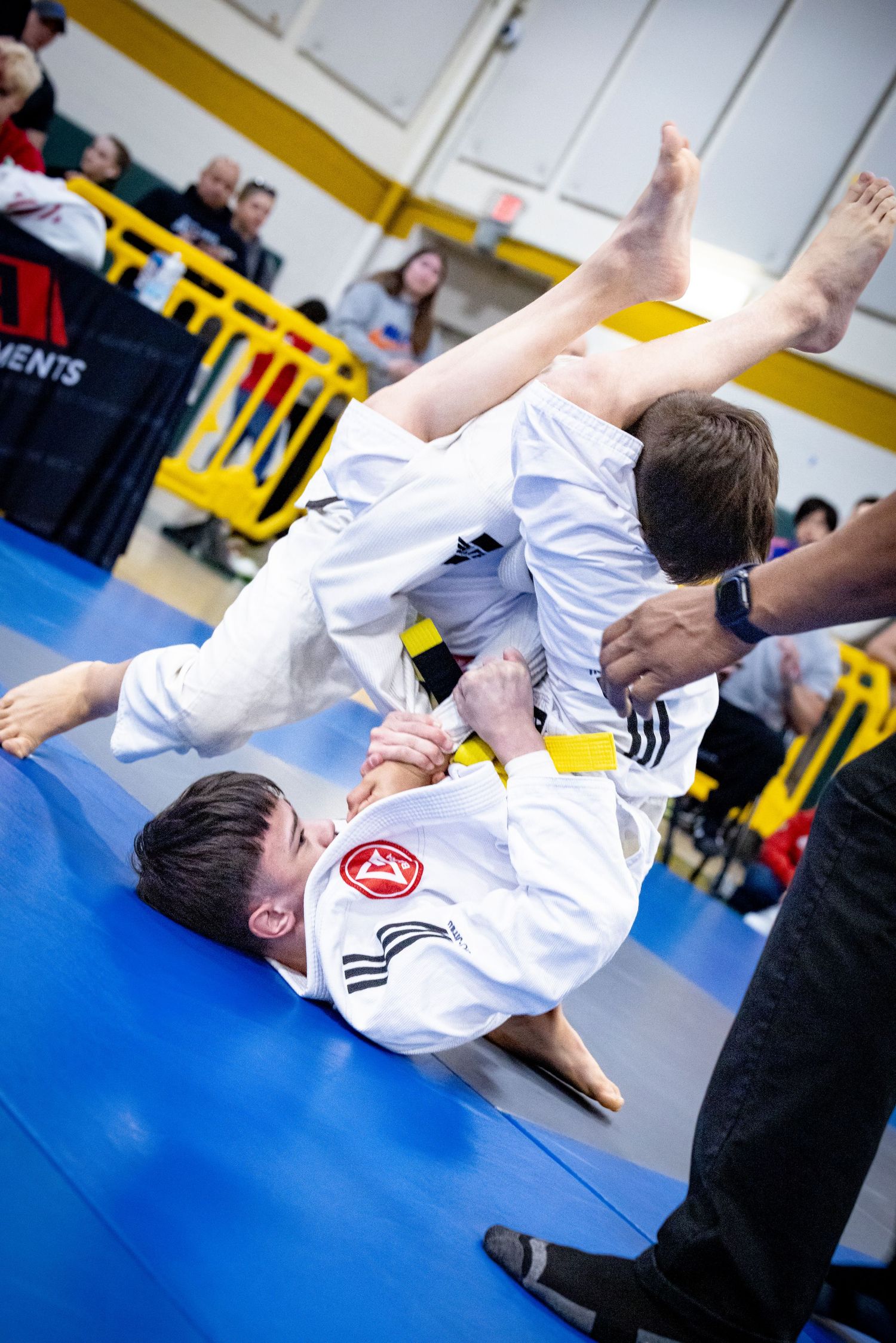 Two competitors in white martial arts uniforms execute dynamic throws during a tournament match.