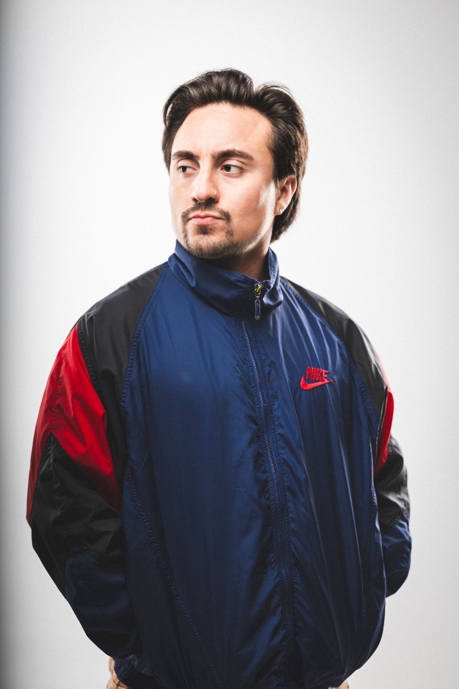 Person wearing blue and red Nike windbreaker jacket against white background.