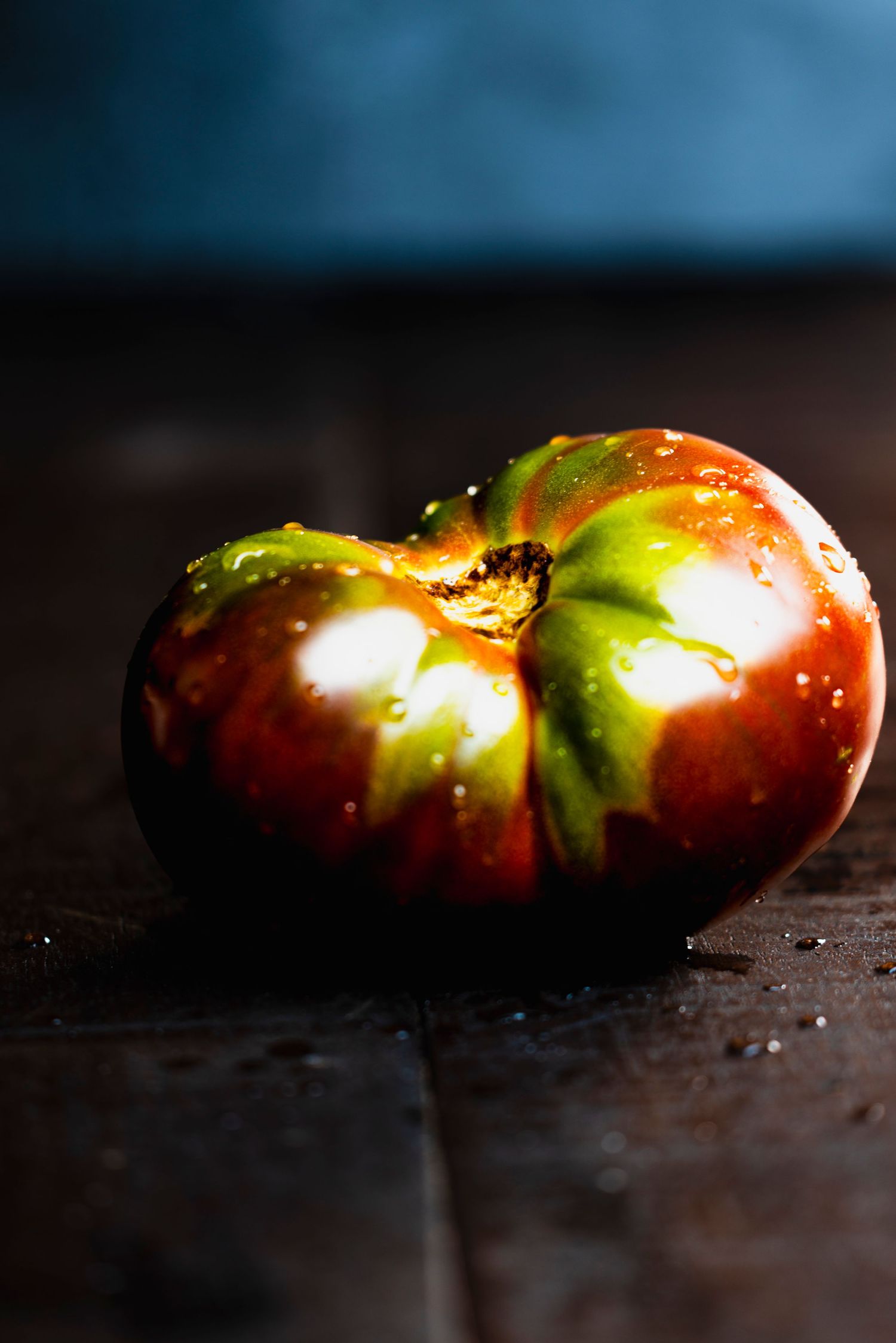 Dark moody photo sequence showing a heirloom tomato's decay process from fresh to rotten against a black background.