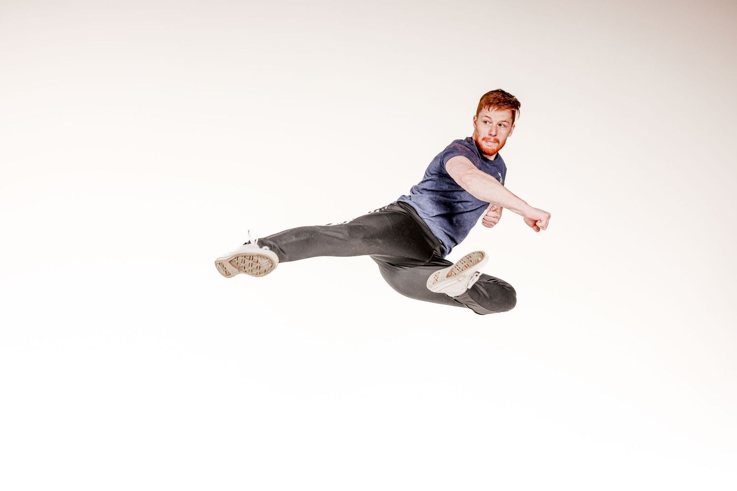 A dancer in blue performs an energetic breakdancing move against a white background.
