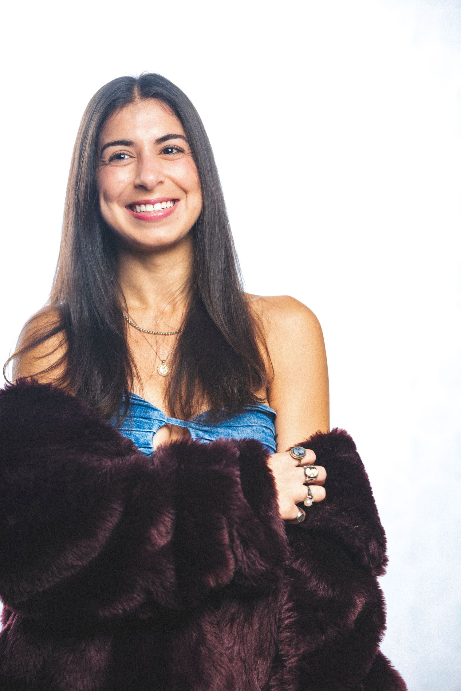 Model wearing plush brown fur coat and blue top poses against white backdrop.
