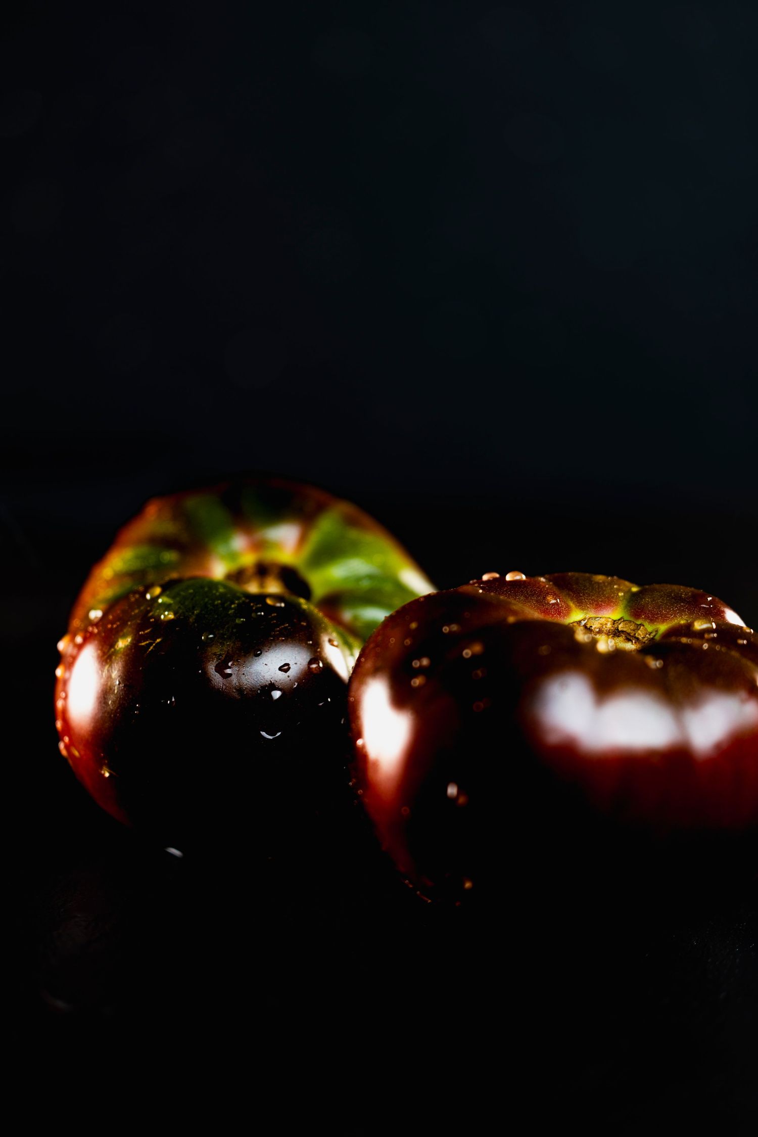 Macro shot of dark purple to black mangosteen fruit segments arranged in a horizontal row against a black background.