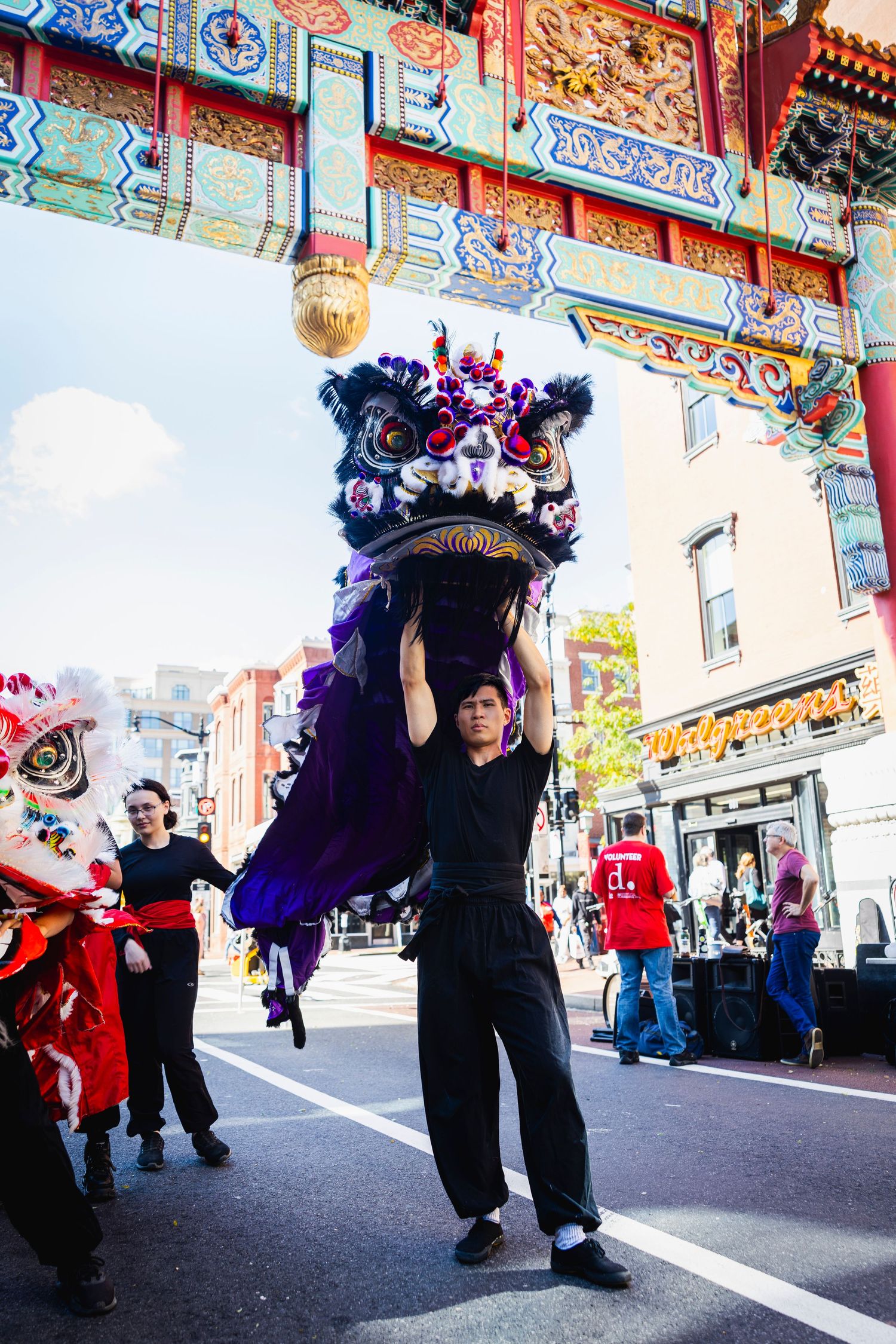 Traditional Chinese dragon dancers perform during cultural celebration under ornate temple architecture in Chinatown Washington D.C.