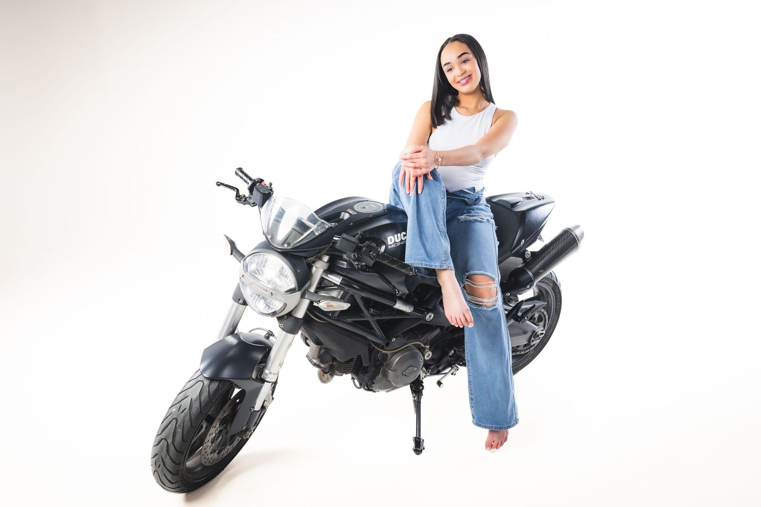 Casual portrait with motorcycle featuring person in jeans and white top.