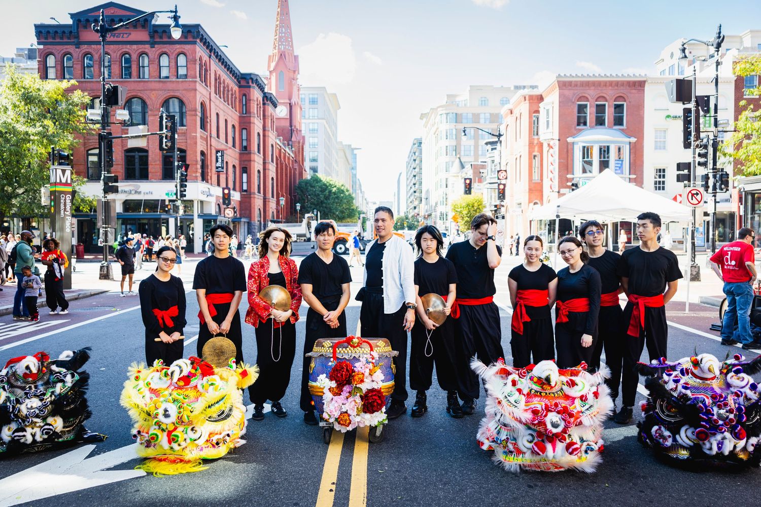 Group performance with dancers in black and red costumes holding colorful props on a city Washington D.C. street in Chinatown.