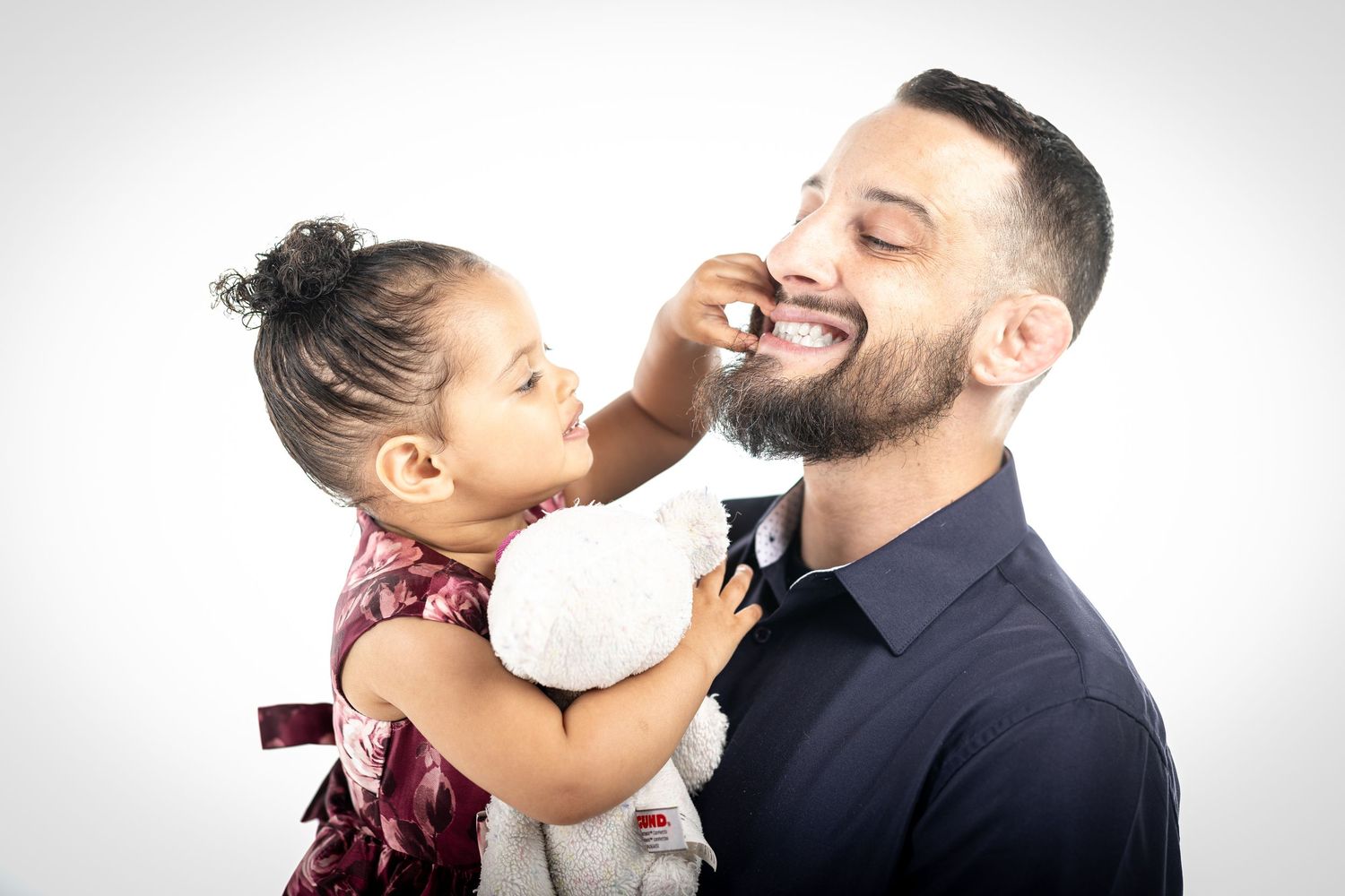 Heartwarming moment showing child playfully touching adult's face against white background.