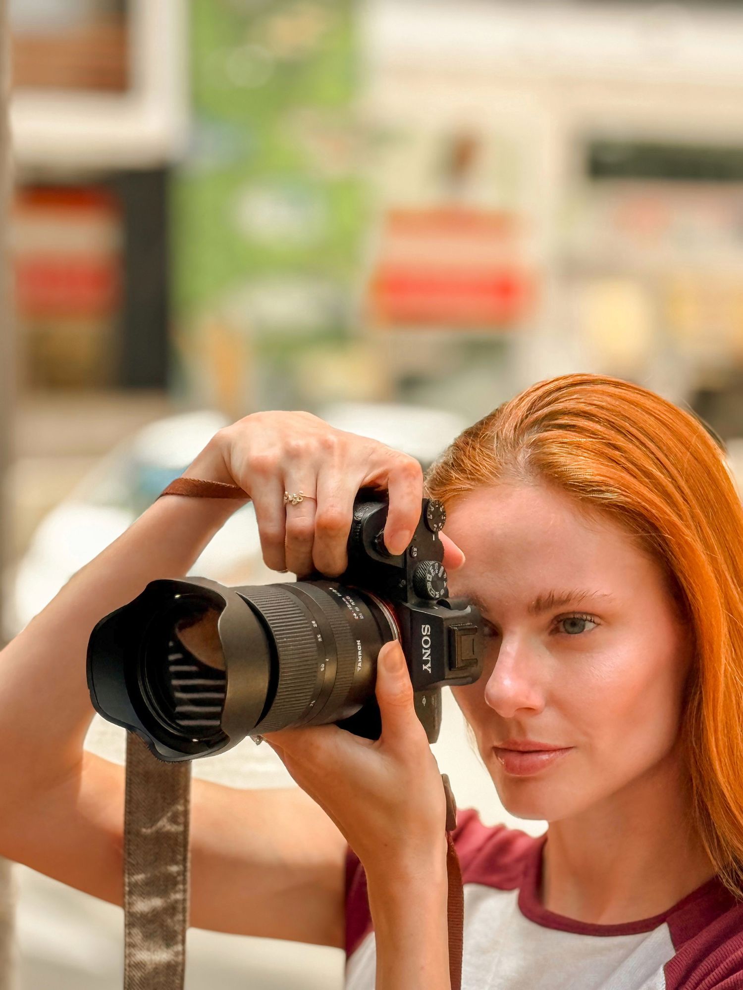 Side profile of Alyssa Campanella holding camera with professional lens in casual outdoor setting.